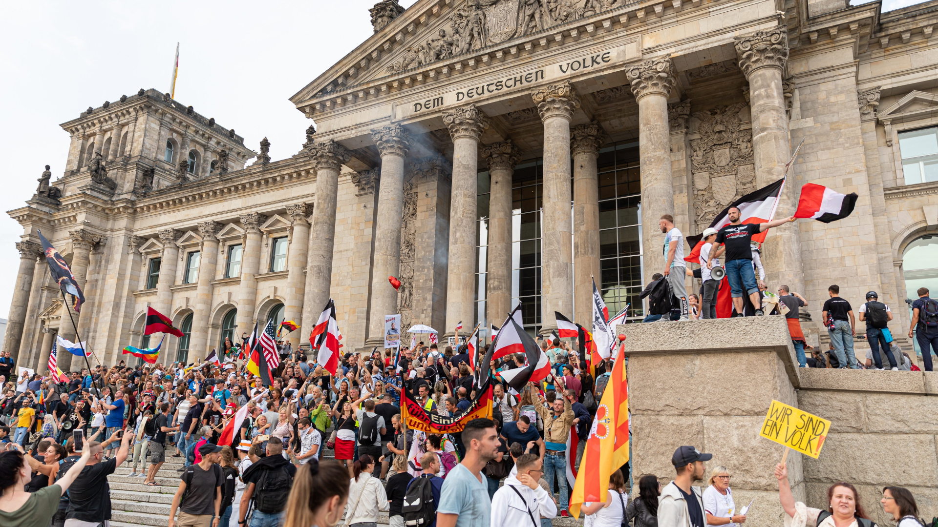 Teilnehmer einer Kundgebung gegen die Corona-Maßnahmen stehen im August 2020 auf den Stufen zum Reichstagsgebäude, zahlreiche Reichsflaggen sind dabei zu sehen. | dpa