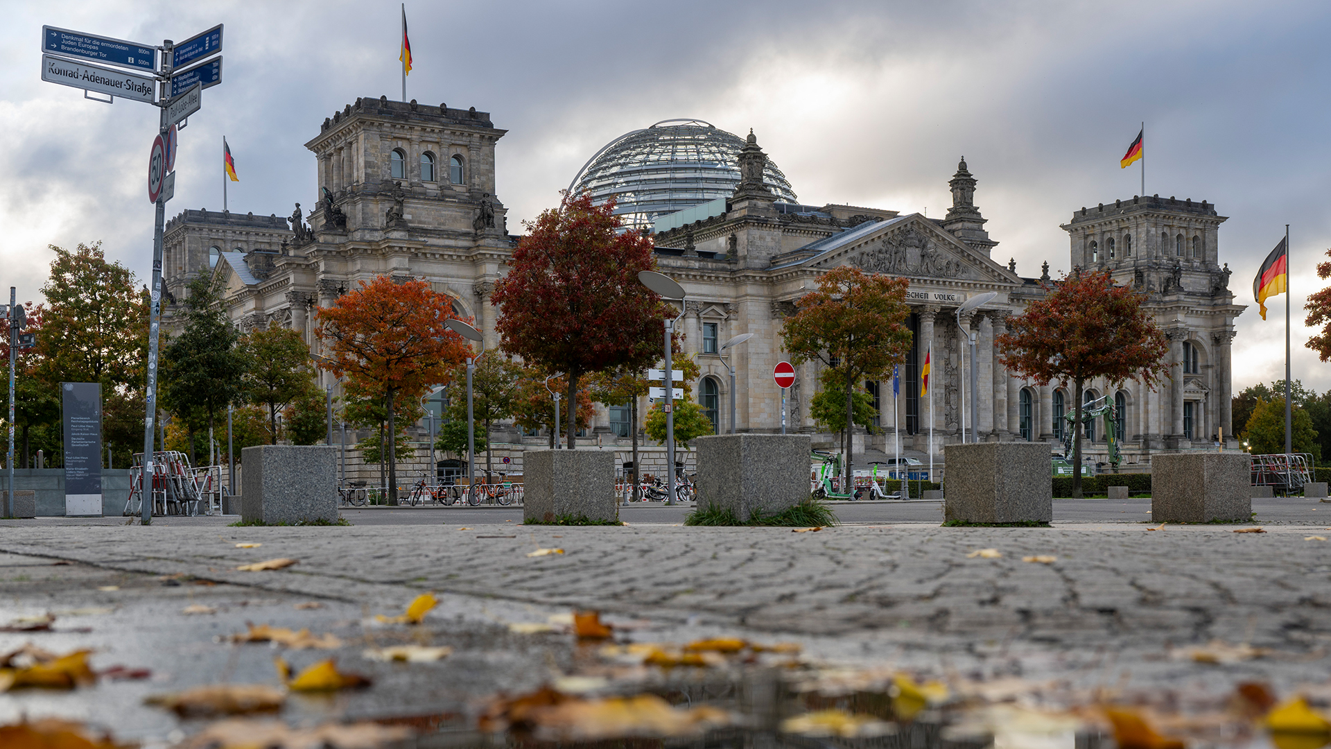 Das Reichstagsgebäude spiegelt sich in einer Pfütze. | dpa