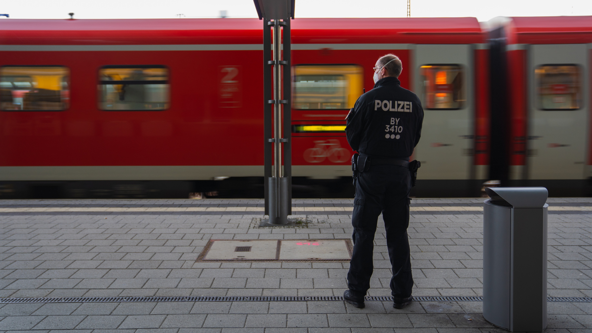 Ein Polizeibeamter blickt am Hofer Bahnhof auf einen einfahrenden Zug. (15. April)