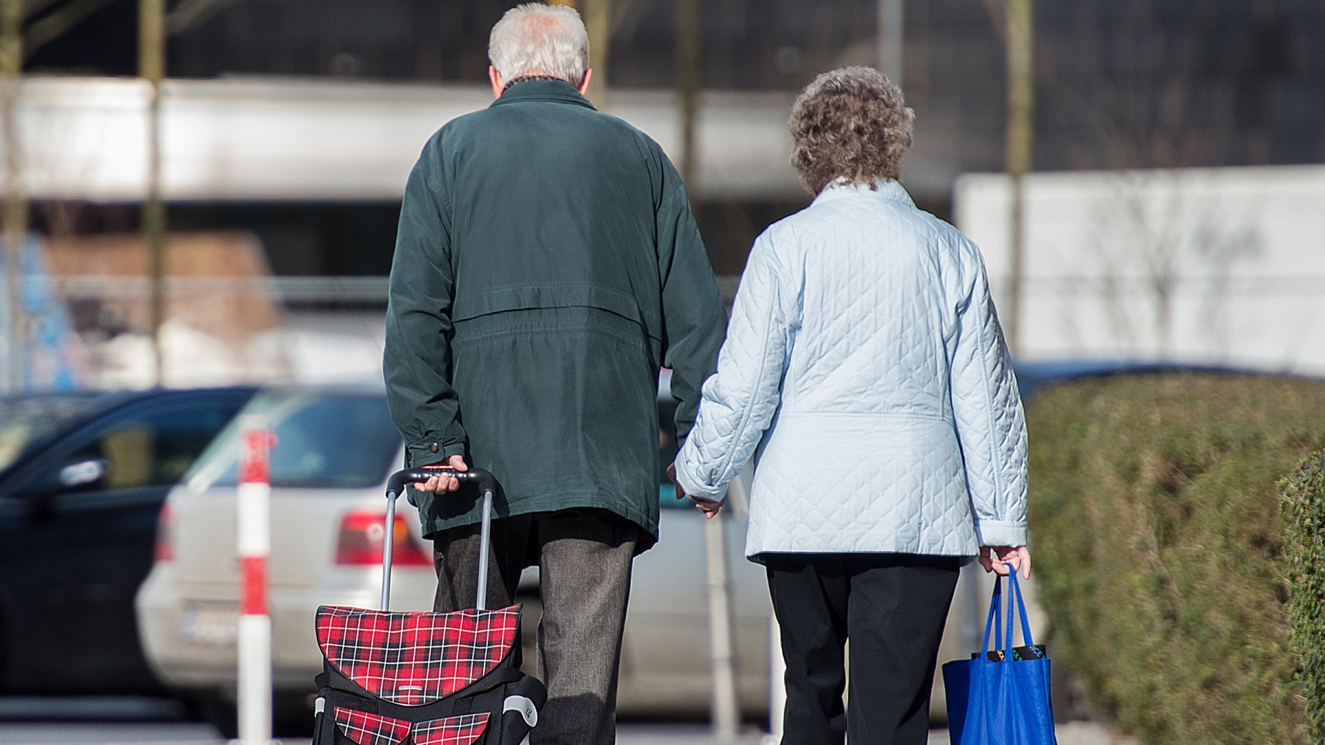 Ein älteres Paar läuft Hand in Hand über den Bürgersteig. | dpa