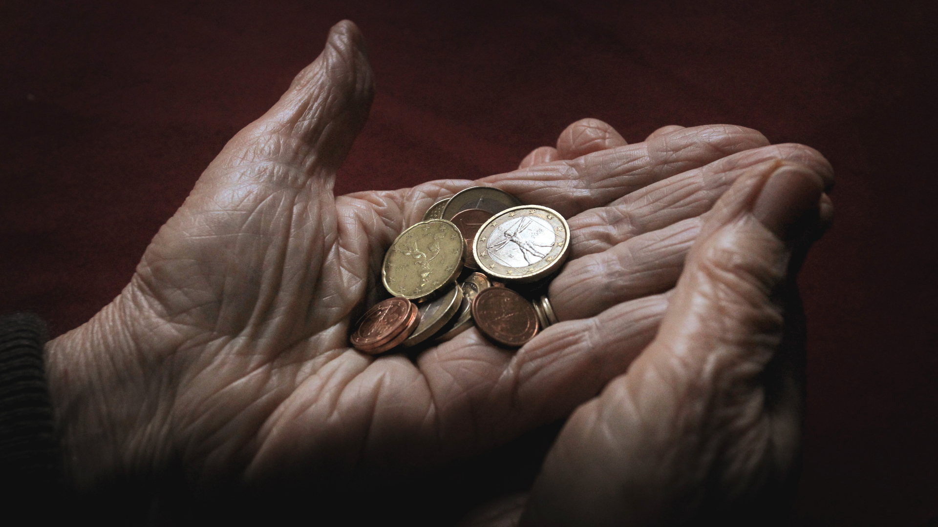 Eine 83-jährige Frau hält verschiedene Euromünzen.  | dpa