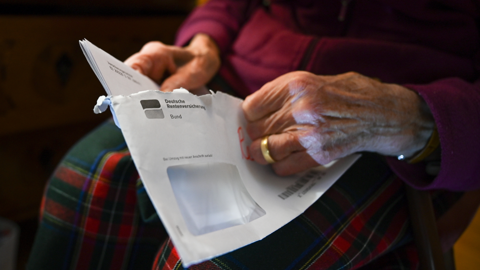 Eine ältere Frau öffnet den Brief mit ihrem Rentenbescheid. | dpa