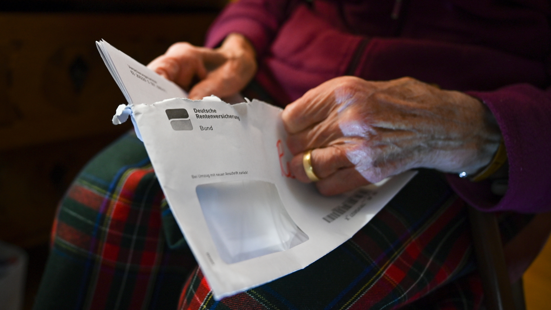 Eine Frau öffnet einen Brief der Deutschen Rentenversicherung. | dpa