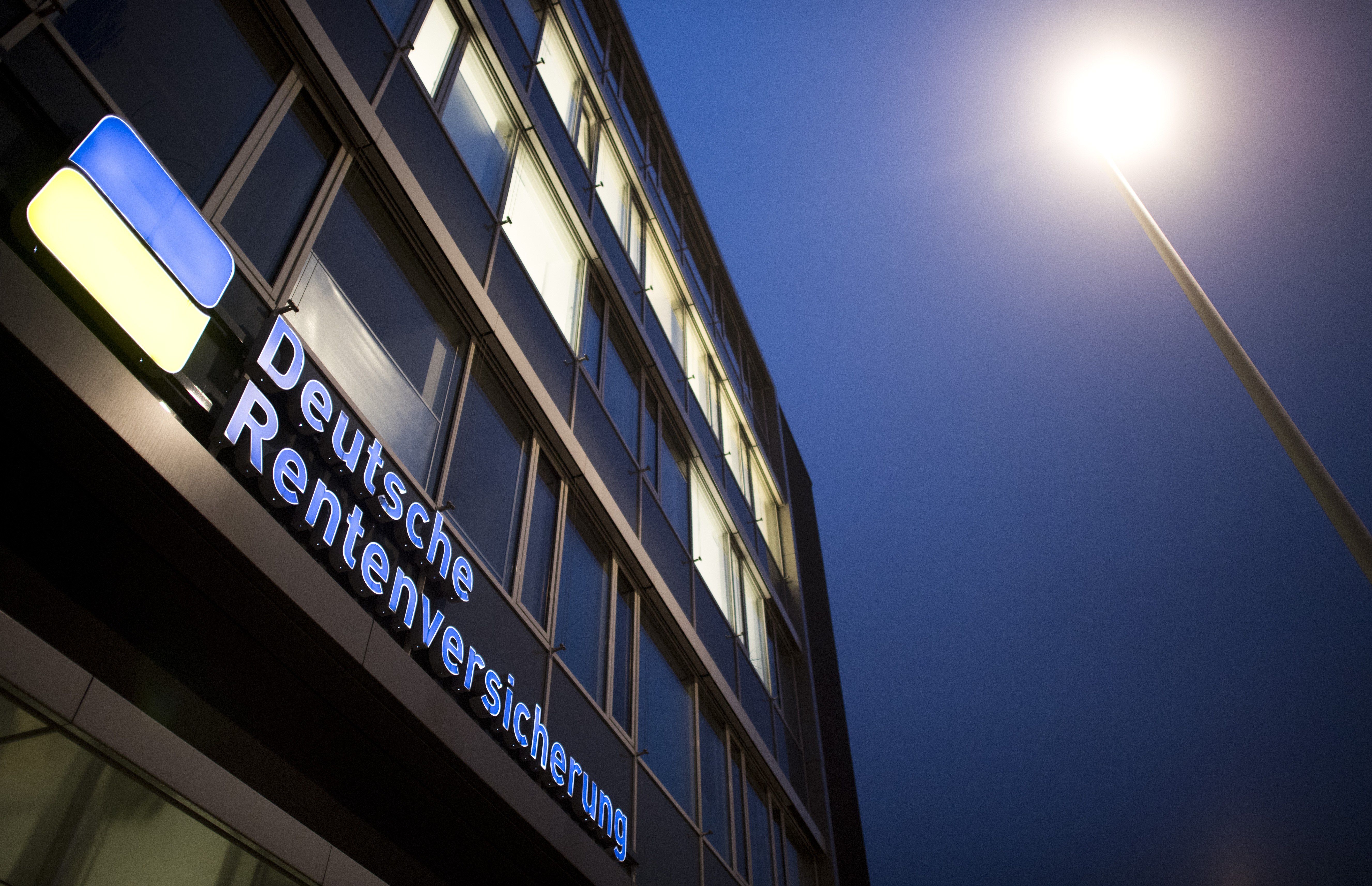 Logo der Deutschen Rentenversicherung leuchtet an einem Gebäudeeingang