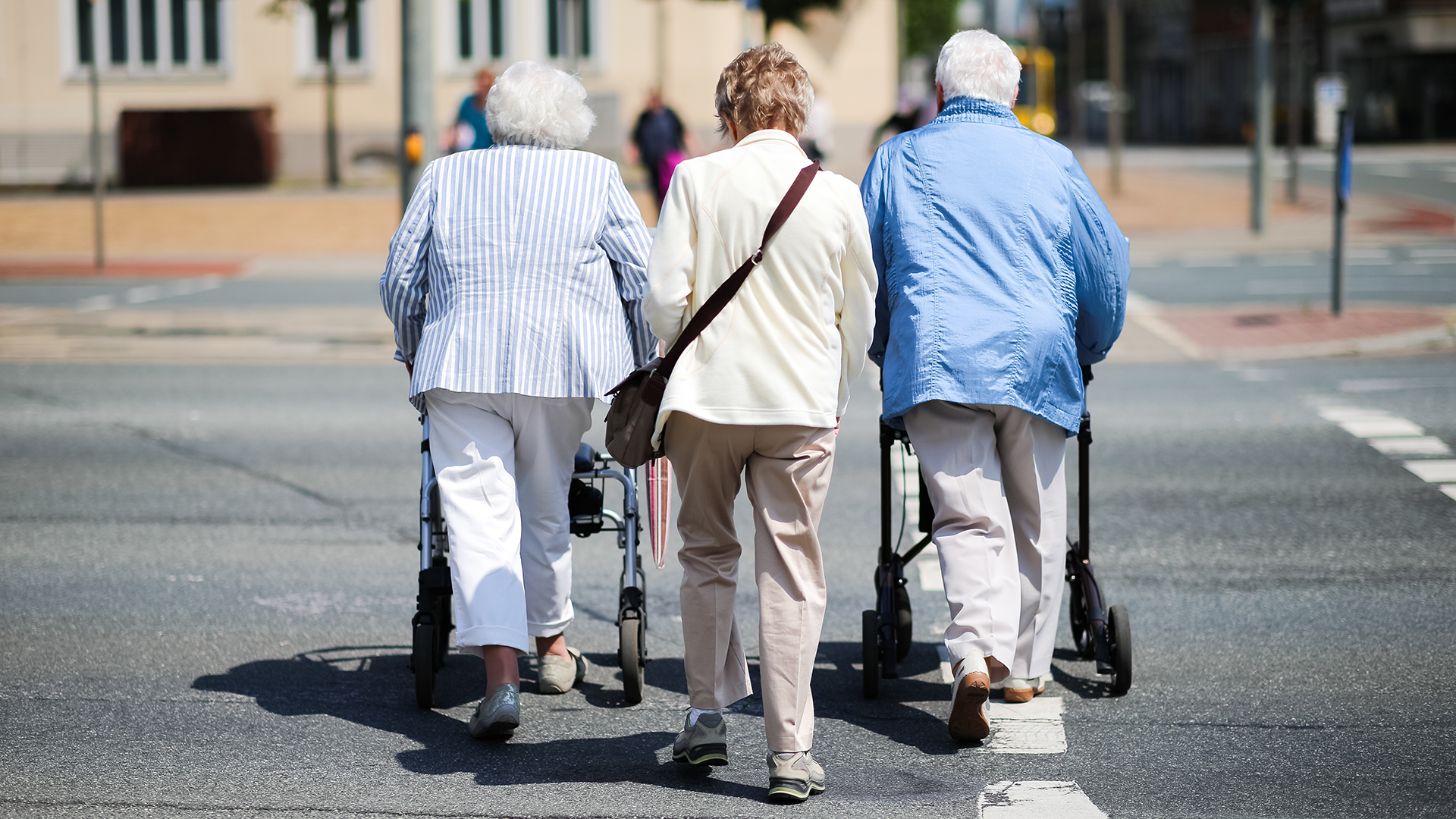 Drei ältere Damen gehen über eine Fußgängerampel