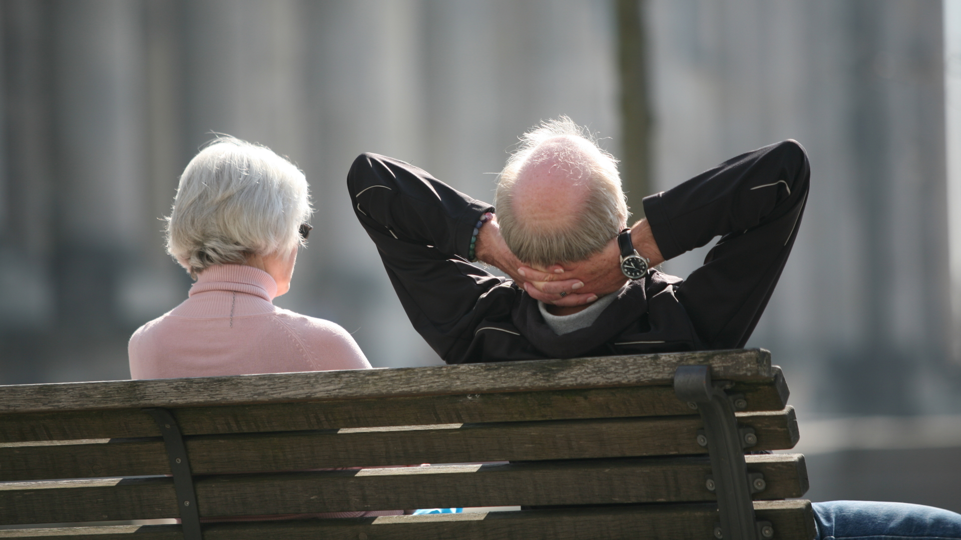 Ein Rentnerpaar sitzt auf einer Parkbank in der Sonne. | dpa