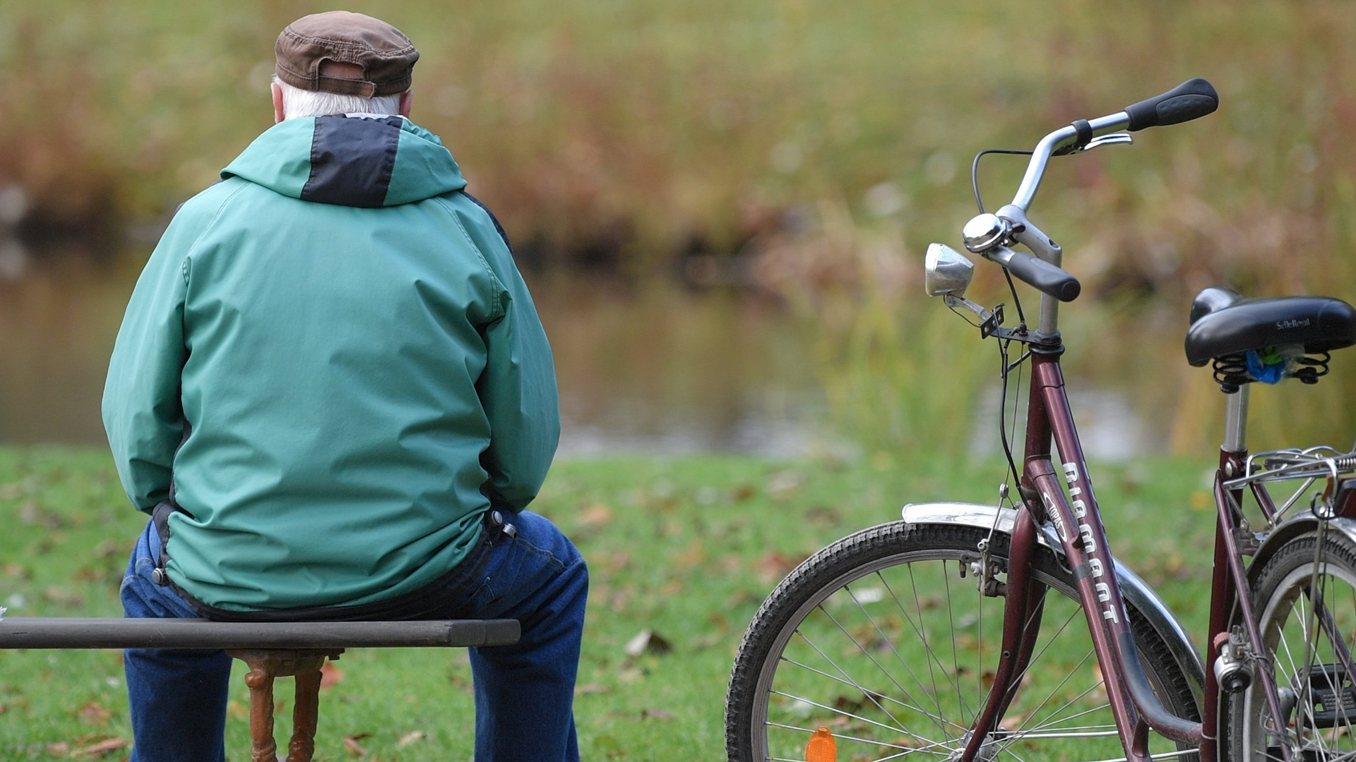 Ein alterer Mann auf einer Bank neben einem Fahrrad