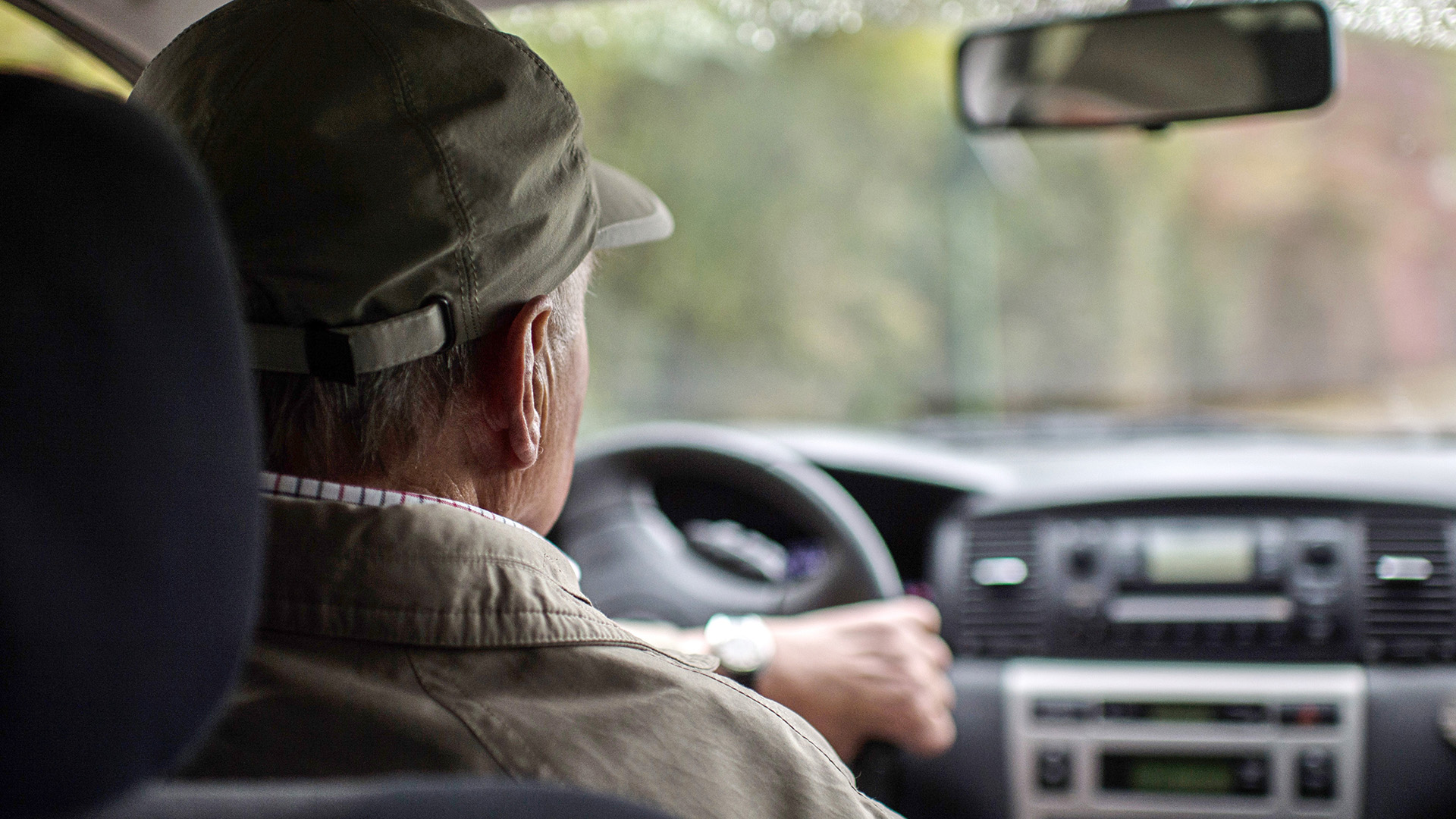 Ein Rentner sitzt am Steuer eines Autos.
