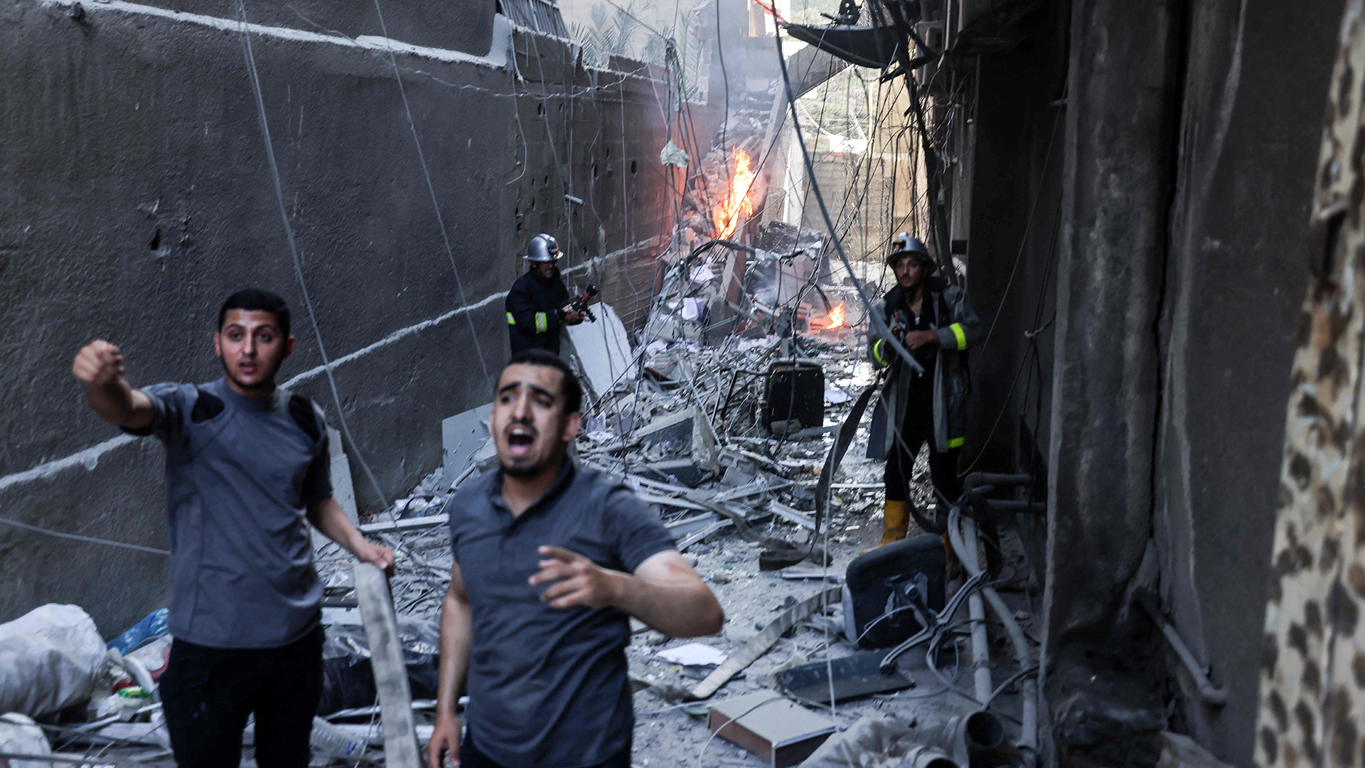 Rettungskräfte und Feuerwehrleute löschen ein Feuer inmitten der Zerstörung nach einem israelischen Luftangriff auf Gaza-Stadt. | AFP