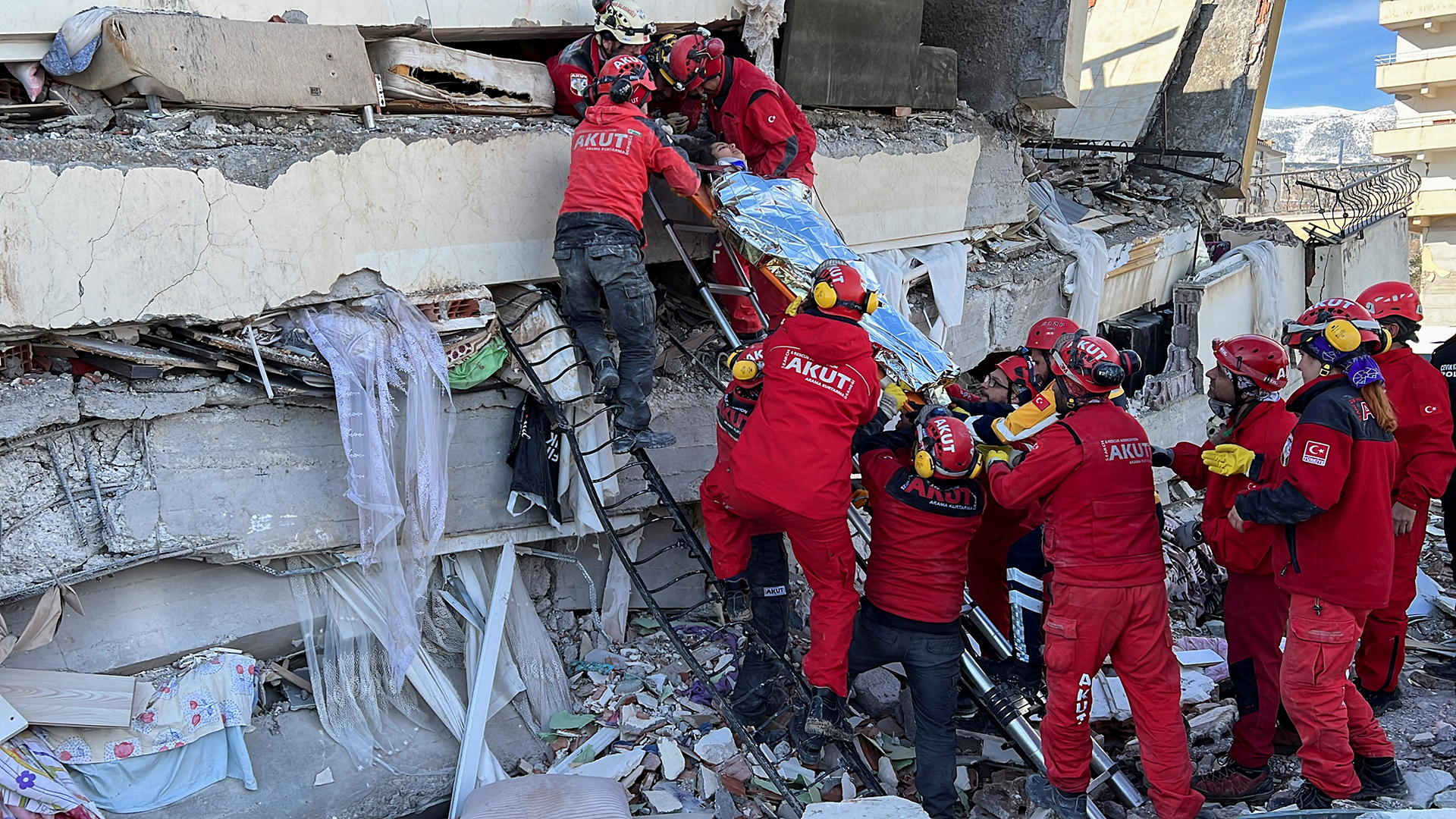 Rettungskräfte tragen eine Frau aus einem eingestürzten Gebäude in Kahramanmaras (Türkei). | REUTERS