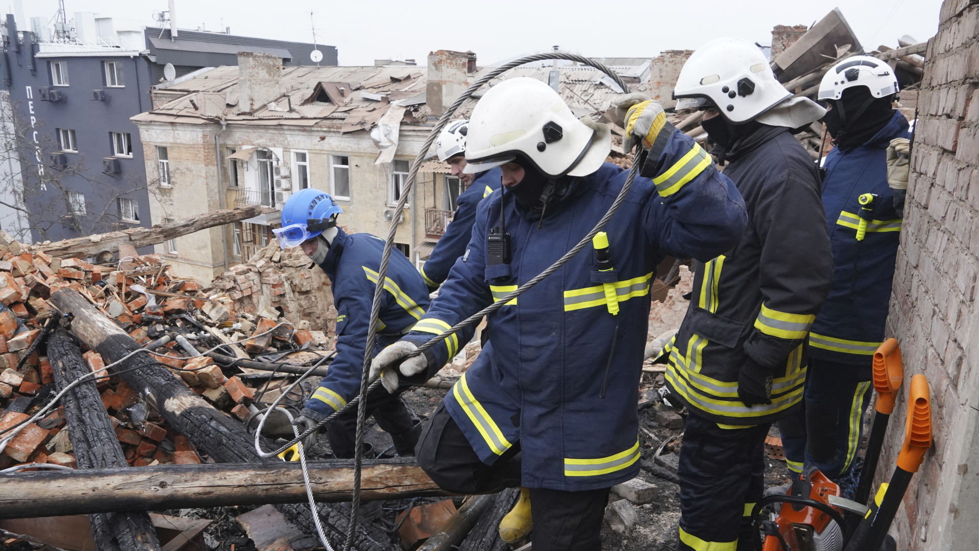 Rettungskräfte auf einem zerstörten Hausdach in Charkiw