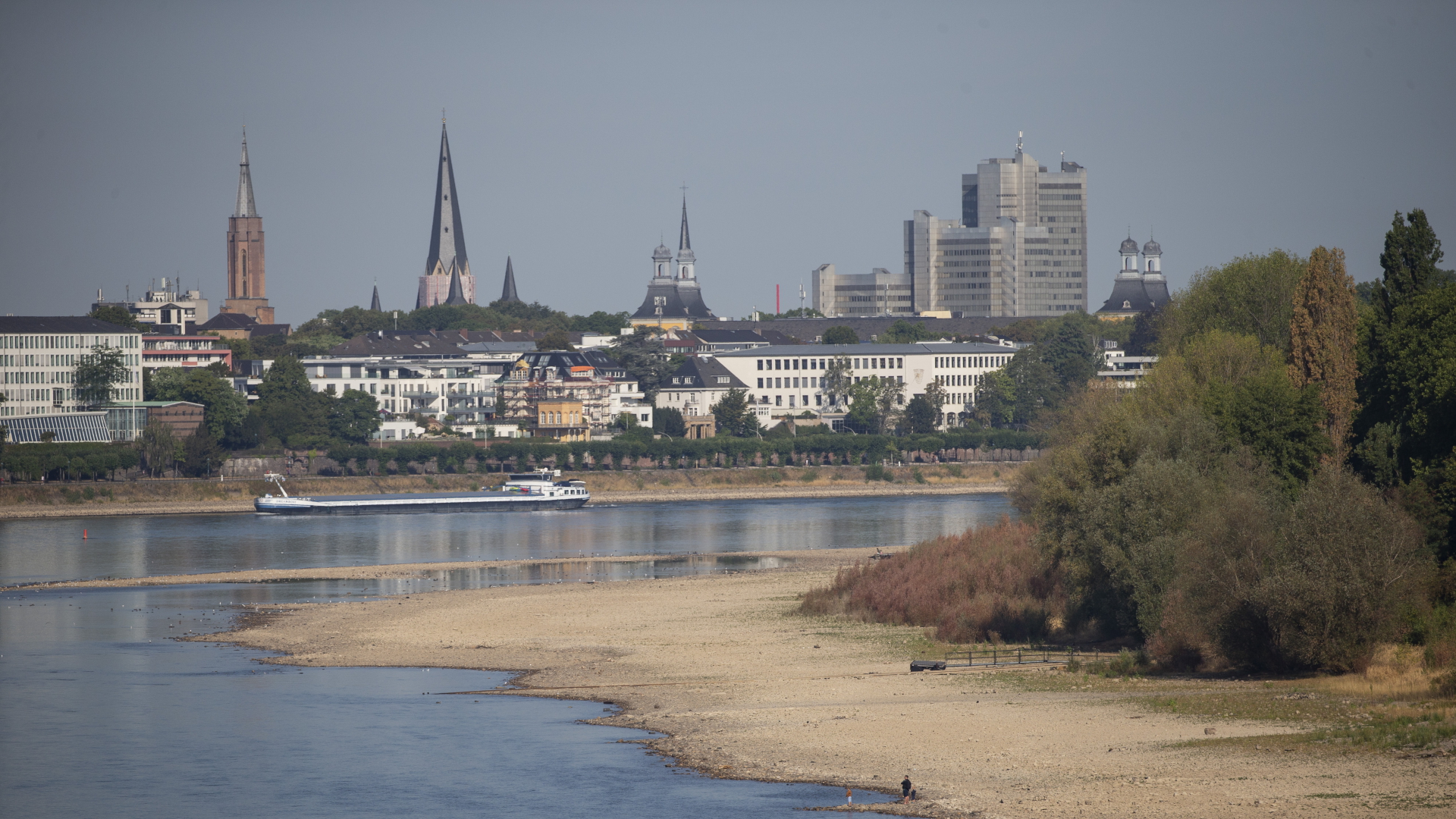 Ein Frachtschiff fährt auf dem Rhein bei Bonn, im Hintergrund ist das Stadtpanorama zu sehen. | dpa
