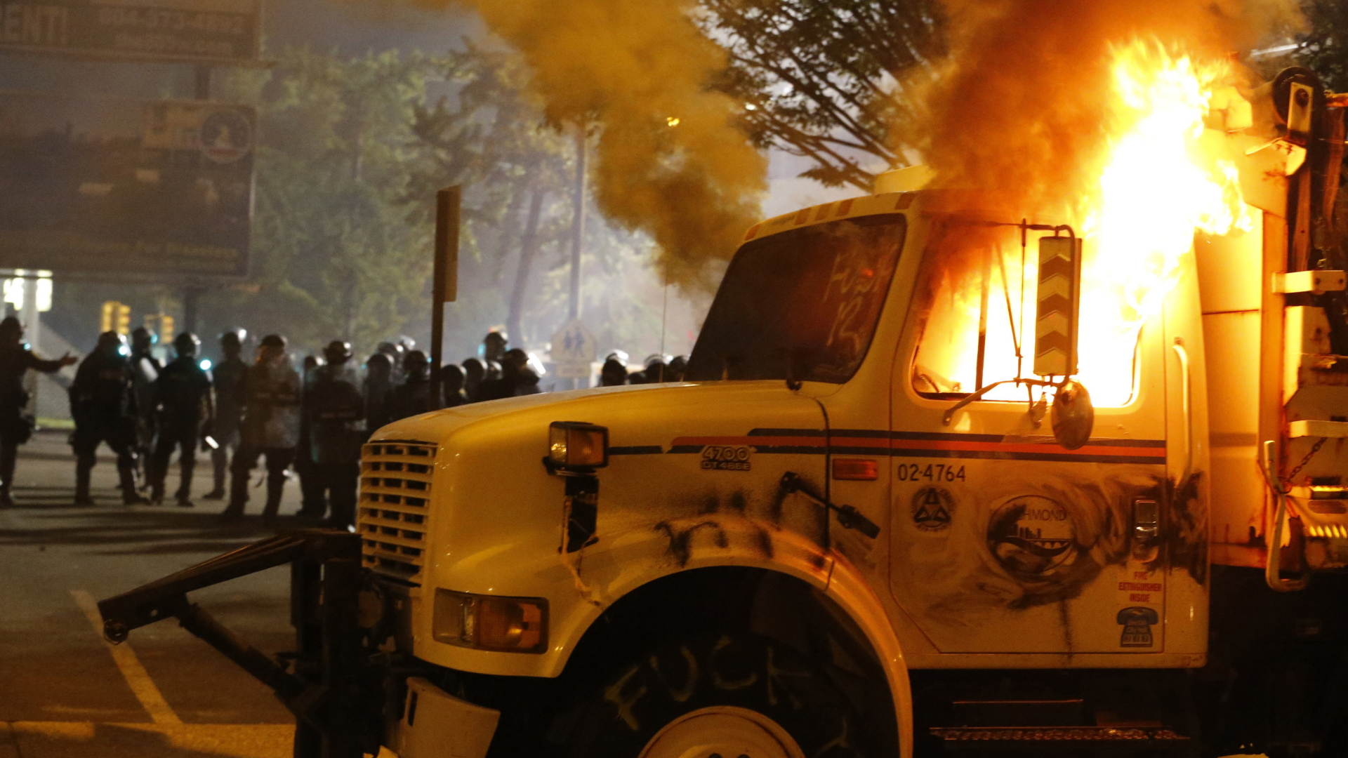 Polizisten stehen hinter einem brennenden Transportfahrzeug in Richmond | AP