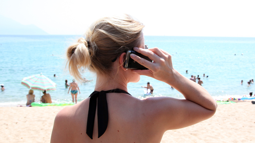 Eine Frau mit Mobiltelefon steht am Strand
