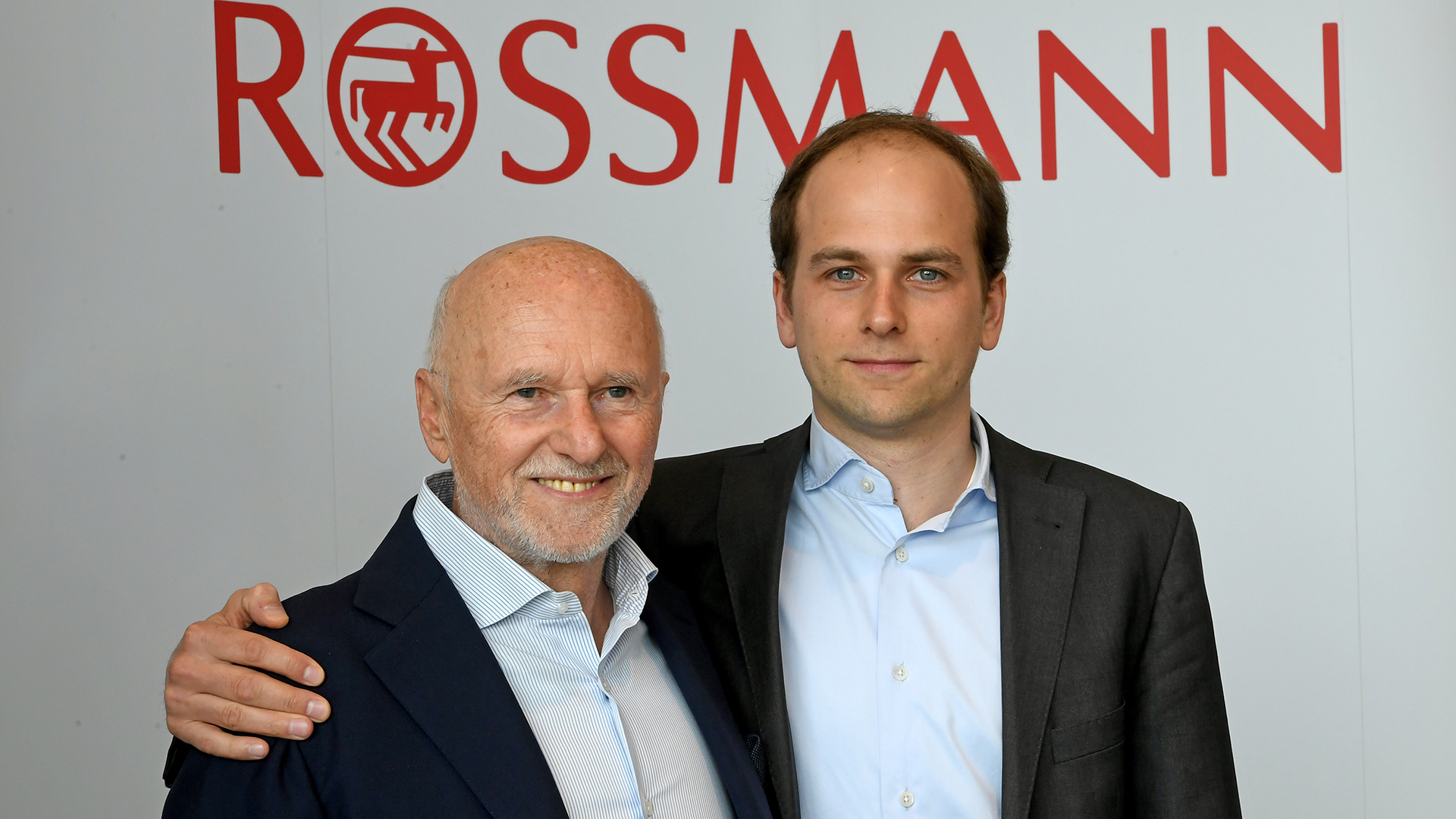 Dirk und Raoul Roßmann (l-r) stehen vor dem Logo der Drogeriekette Rossmann. (Archivbild vom 12.04.2018) | picture alliance / Holger Hollem