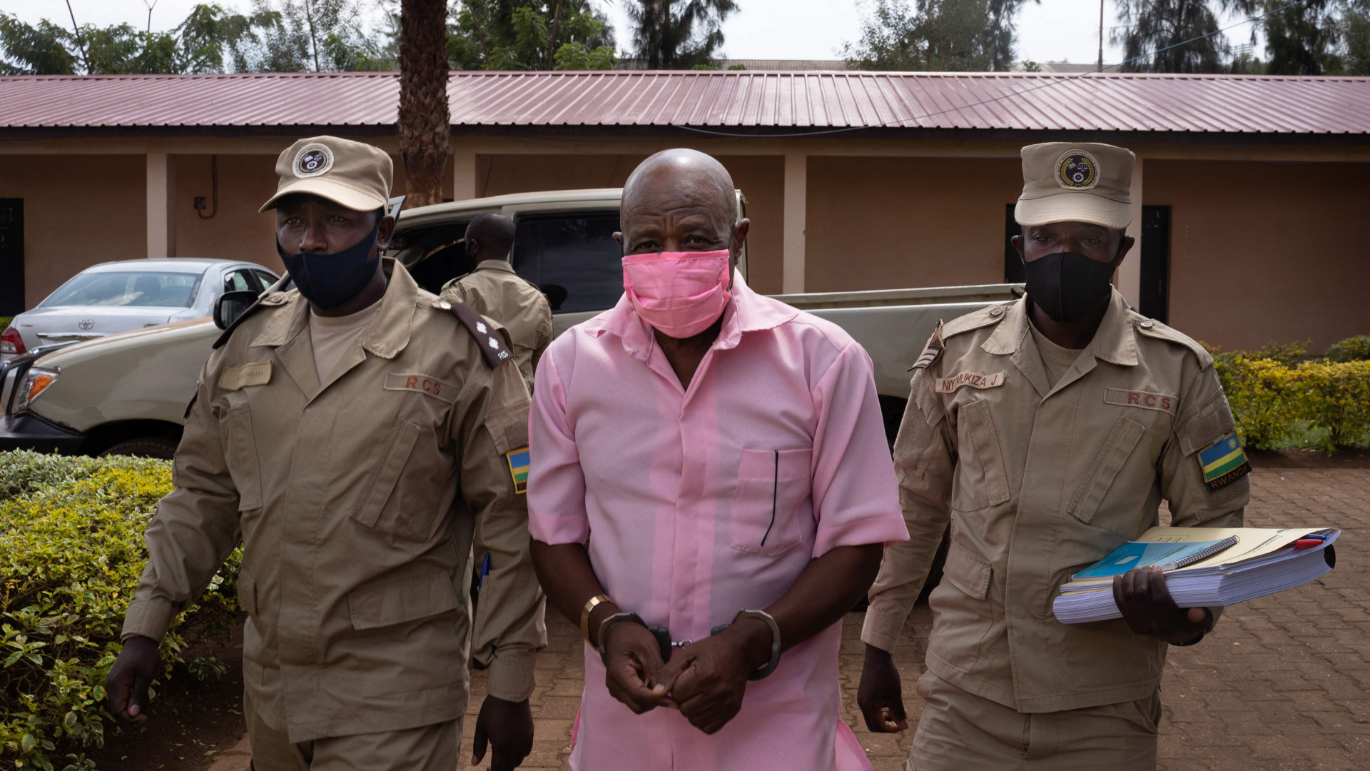 Paul Rusesabagina (M),  auf dem Weg zum Gericht in Kigali, begleitet von zwei Gefängniswärtern (Archivbild 2020). | AFP