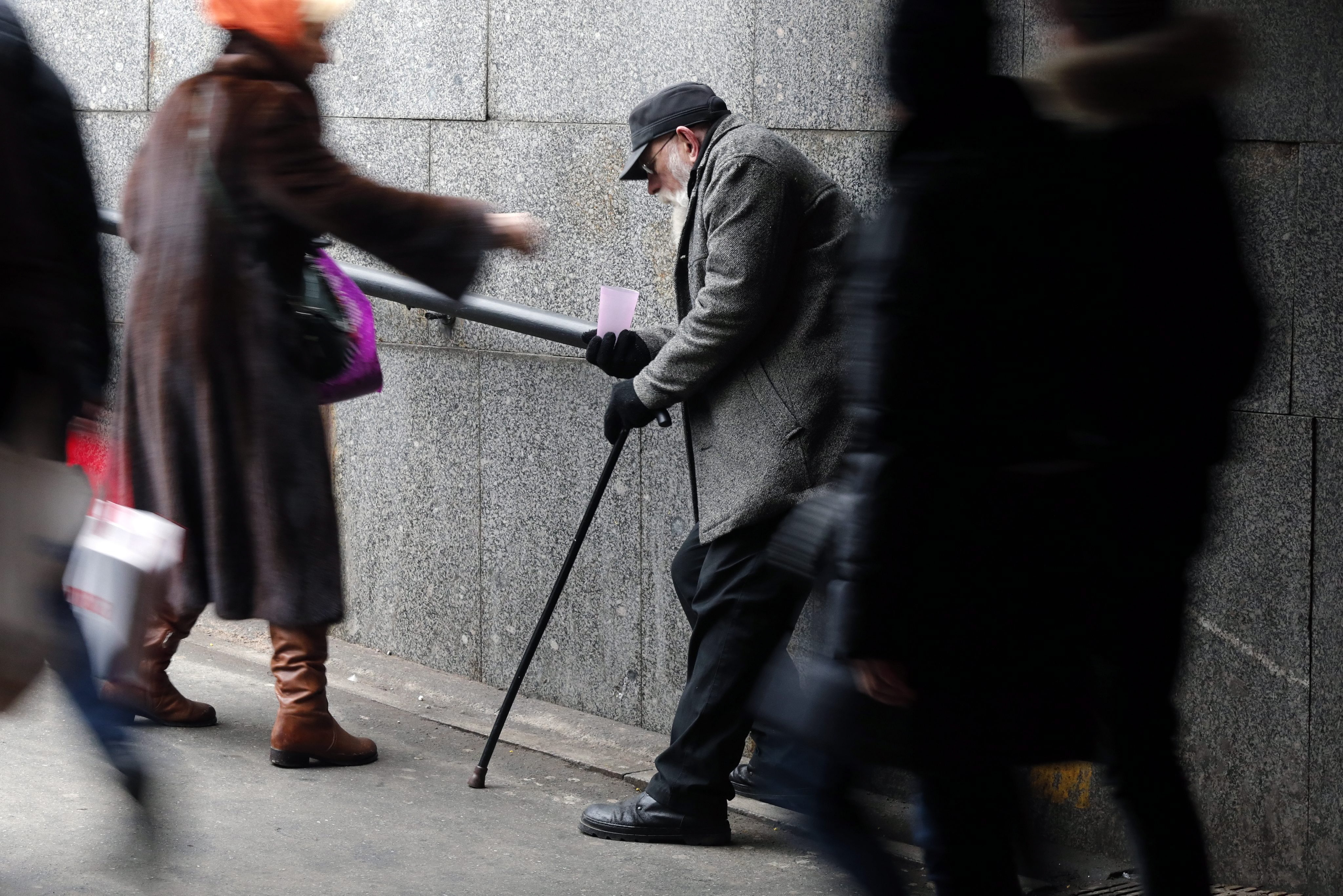 Eine Passantin spendet einem alten Mann in St. Petersburg (Russland) Geld