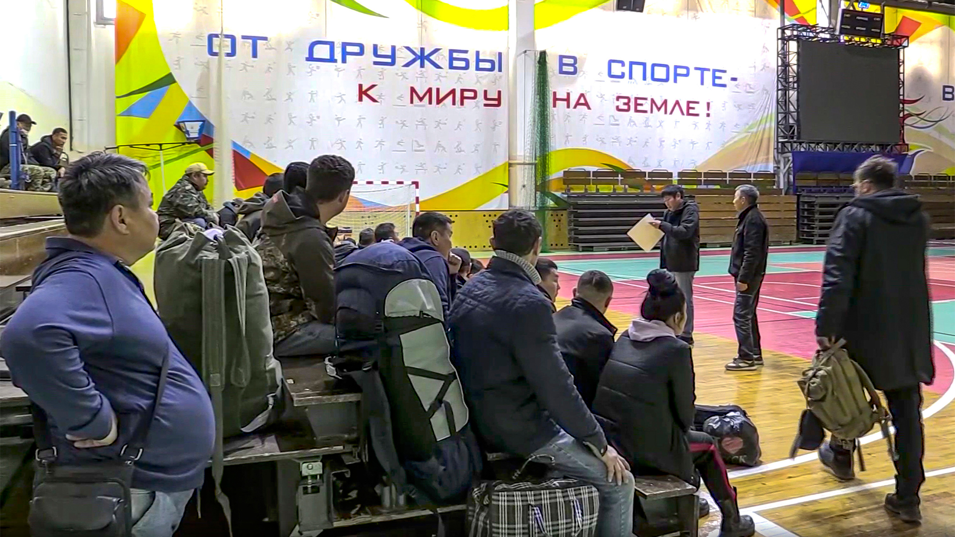Einberufene russische Männer haben sich in einer Turnhalle versammelt. | AP