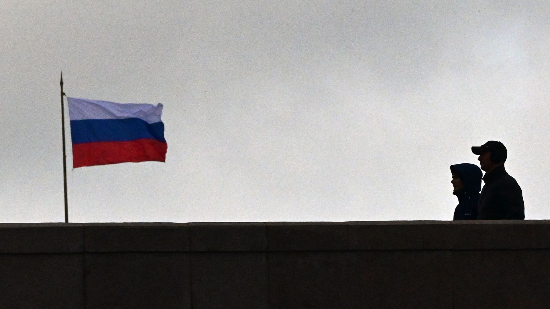 Passanten gehen in Moskau (Russland) an einer russischen Flagge vorbei. | AFP