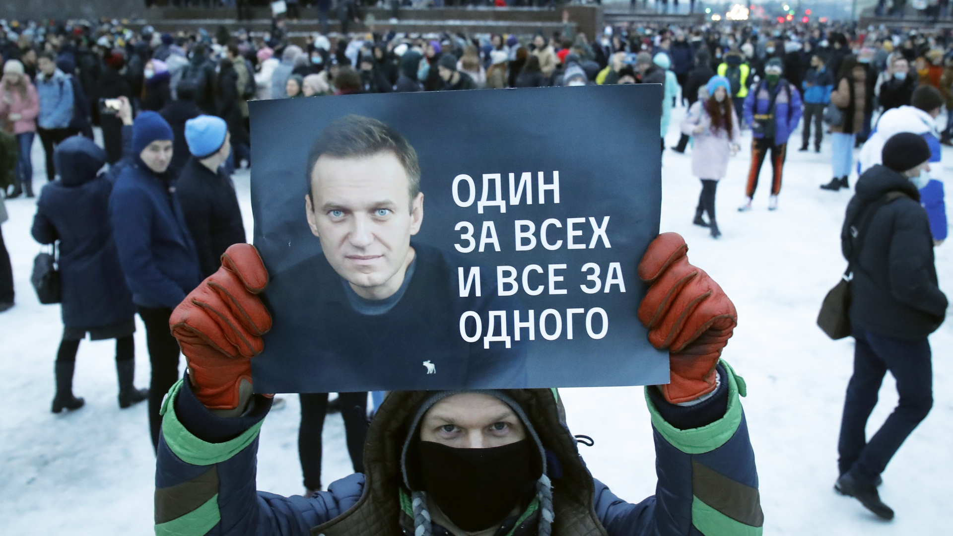 Ein Demonstrant hält ein Plakat mit einem Bild von Nawalny und dem Spruch: "Einer für alle, alle für einen!" | AP