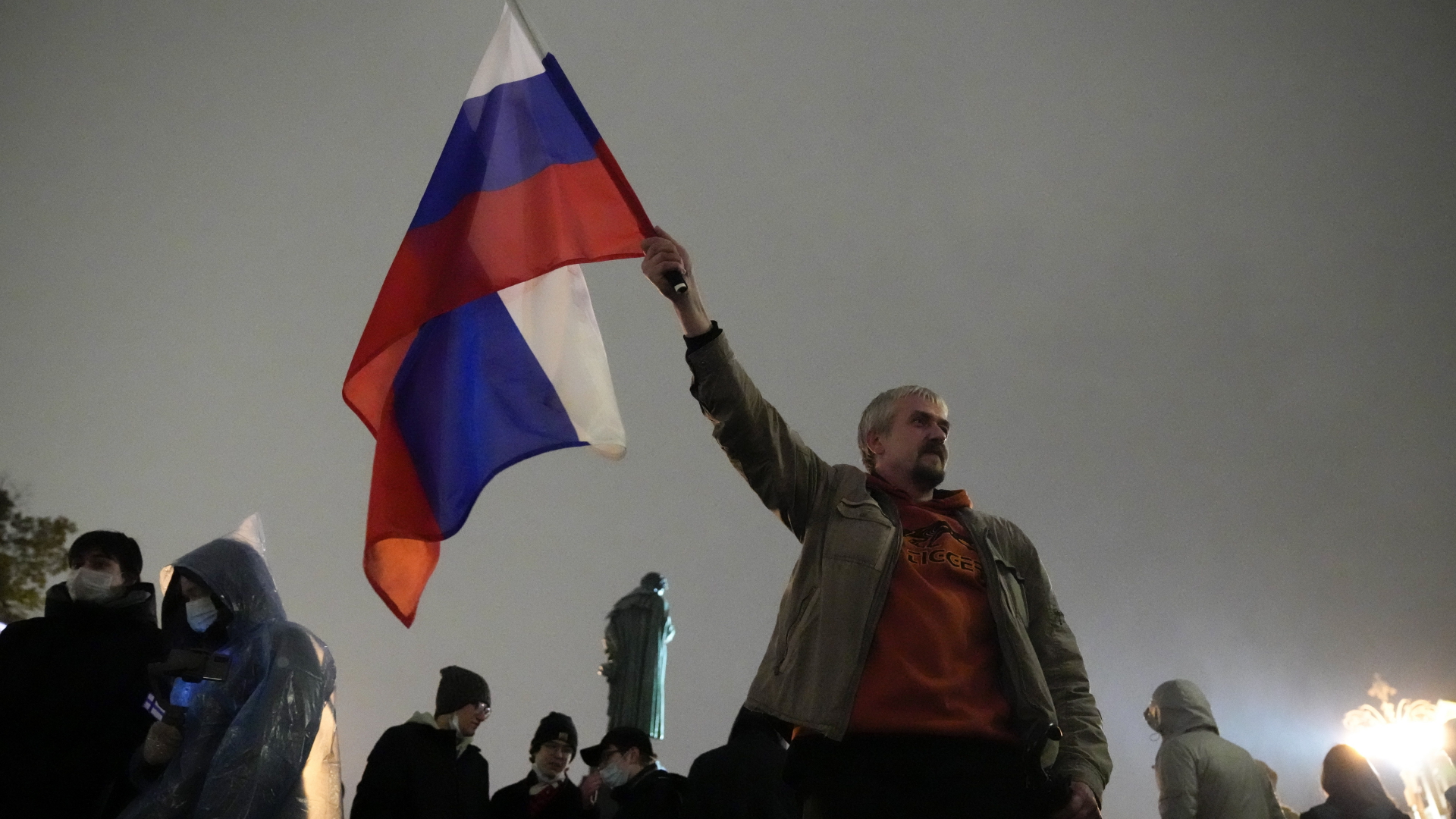 Ein Mann hält eine russische Nationalflagge in der Hand. | dpa