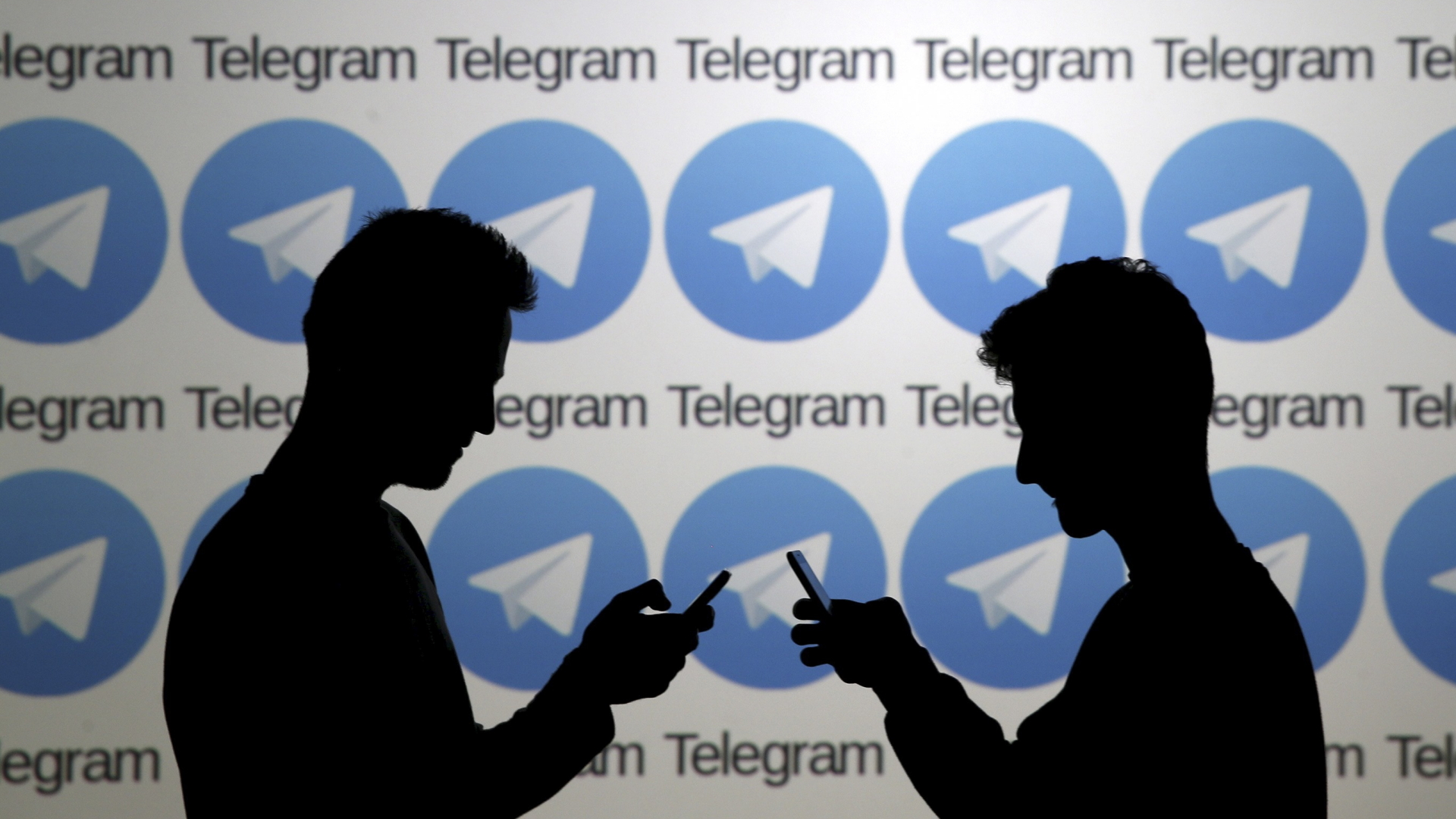 Zwei Mobilfunknutzer vor einer Wand mit Logos des russischen Messengerdienstes Telegram | REUTERS