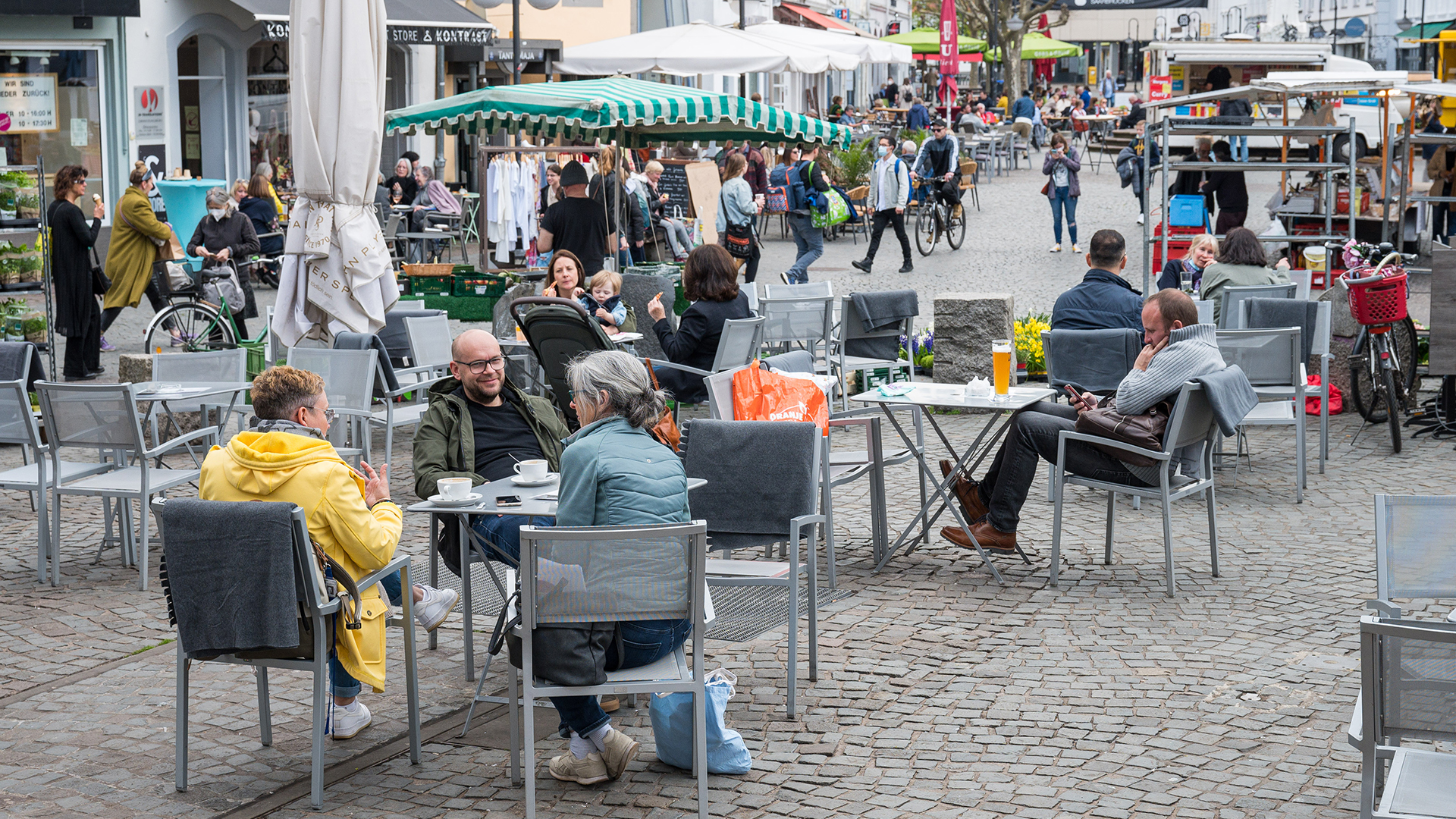 Auf dem St. Johanner Markt in Saarbrücken sitzen Menschen im Außenbereich von Gastronomiebetrieben. 