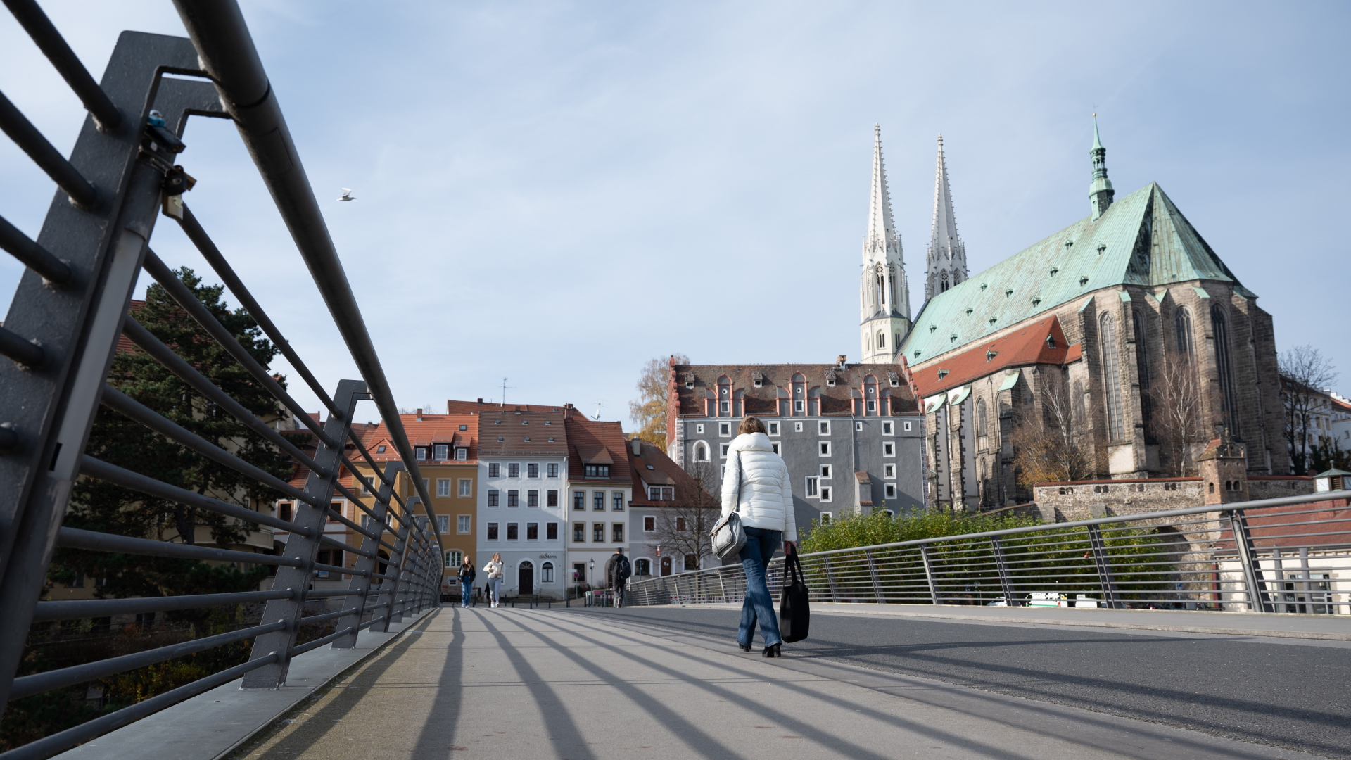 Eine Passantin geht auf der Altstadtbrücke über die Neiße vor der Pfarrkirche St. Peter und Paul in Görlitz. | dpa