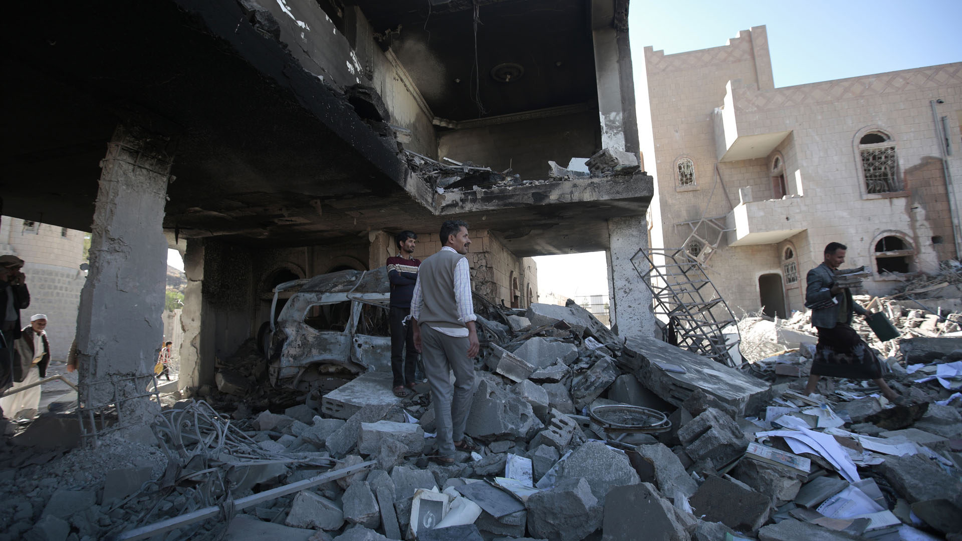 Eine Gruppe Männer inspiziert die Schäden nach einem Luftangriff der saudischen Koalition in Sanaa. | picture alliance/dpa/AP