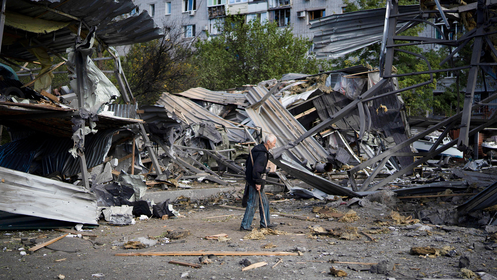 Ein älterer Mann geht an einem Autohaus vorbei, das nach einem russischen Angriff in Saporischschja (Ukraine) zerstört wurde.