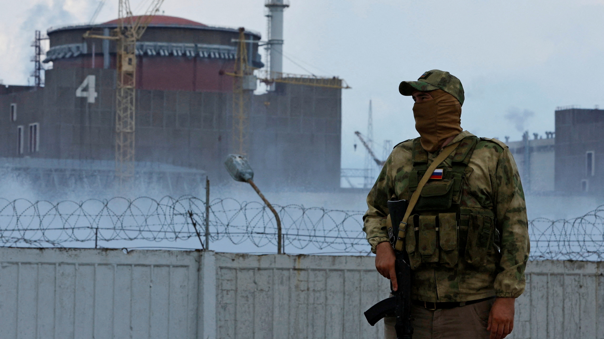 Ein Soldat mit russischer Flagge auf der Uniform vor dem ukrainischen Atomkraftwerk Saporischschja.