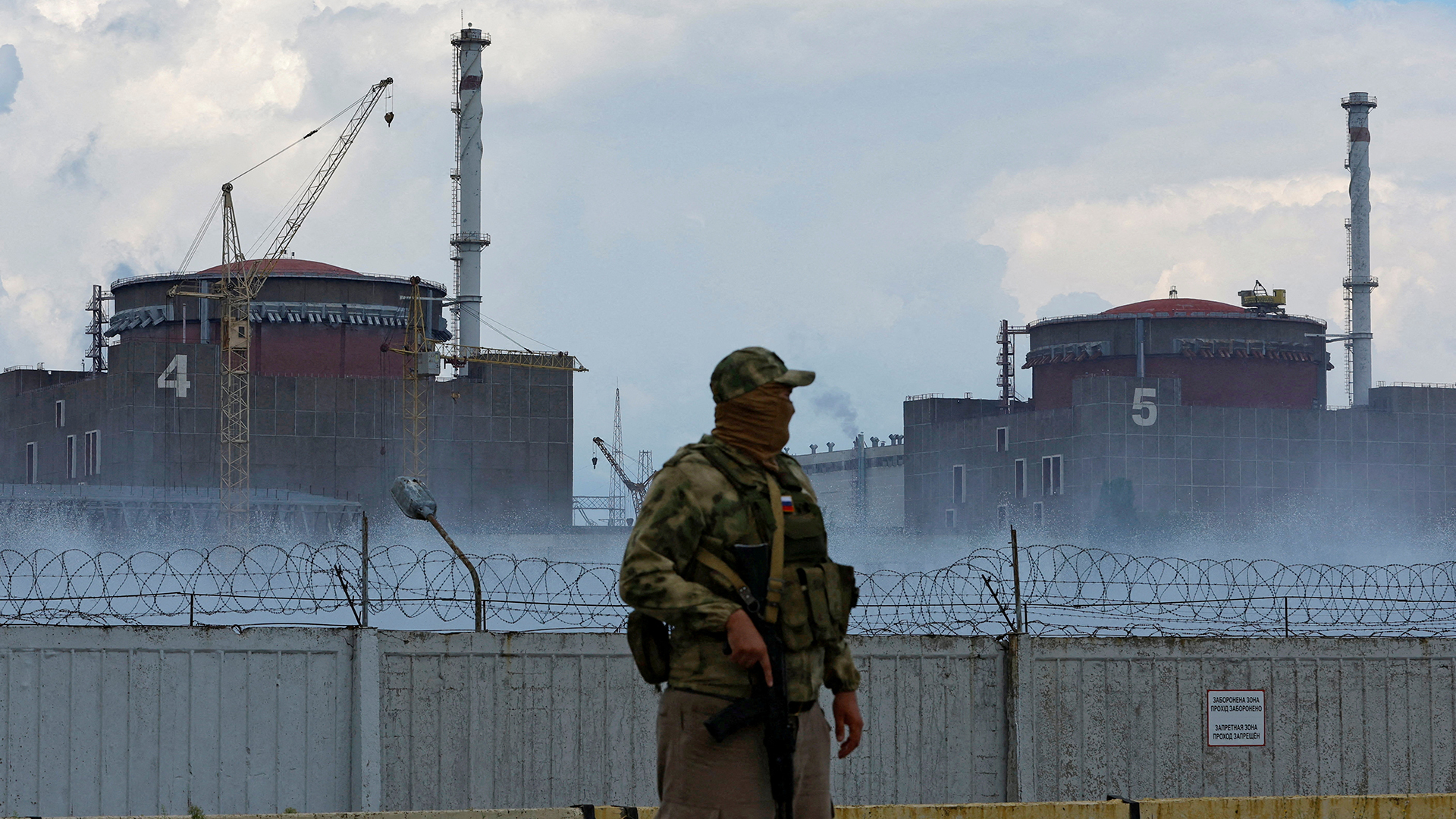 Ein Soldat mit russischer Flagge auf der Uniform vor dem ukrainischen Atomkraftwerk Saporischschja. | REUTERS