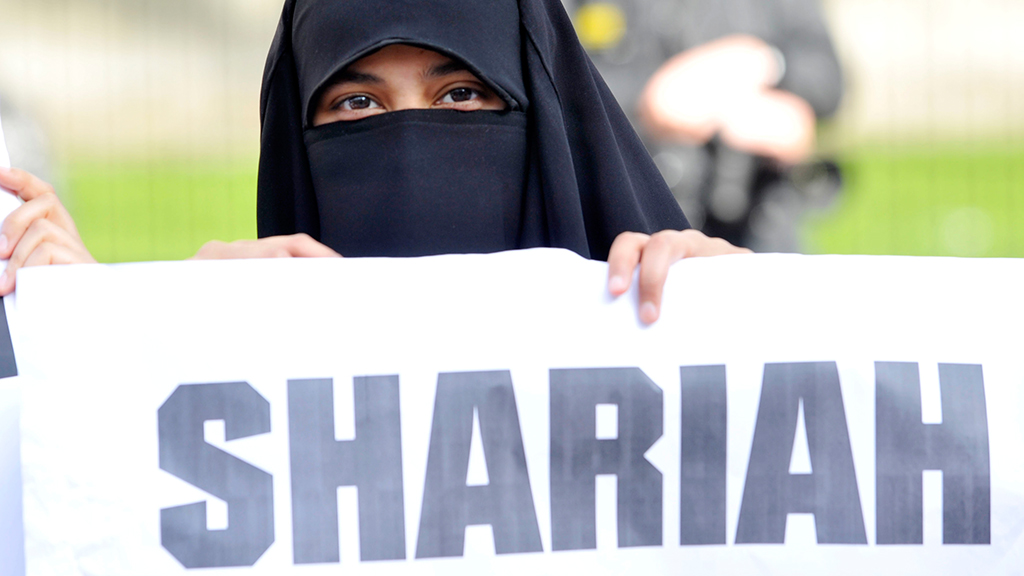 Eine verschleierte Frau hält ein Schild mit der Aufschrift Shariah | picture alliance / Photoshot
