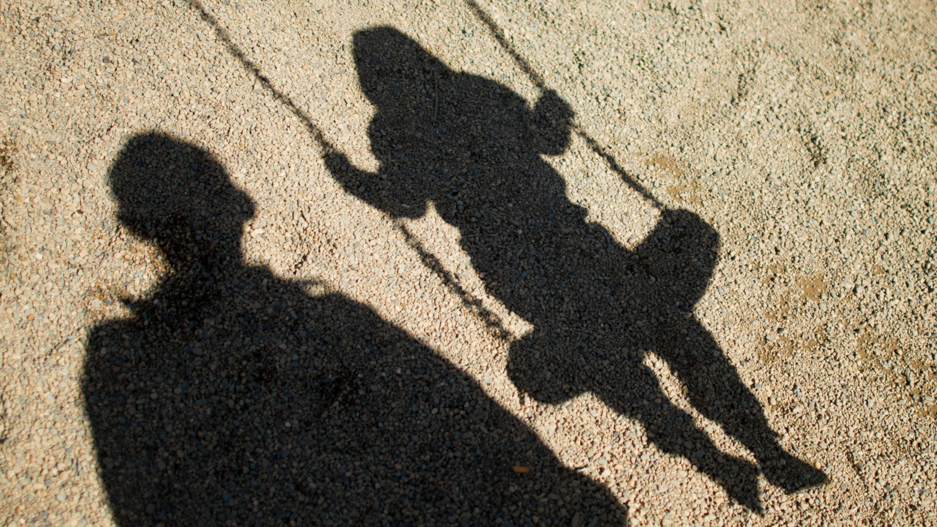 Schatten von Kind auf Schaukel und Mann | dpa