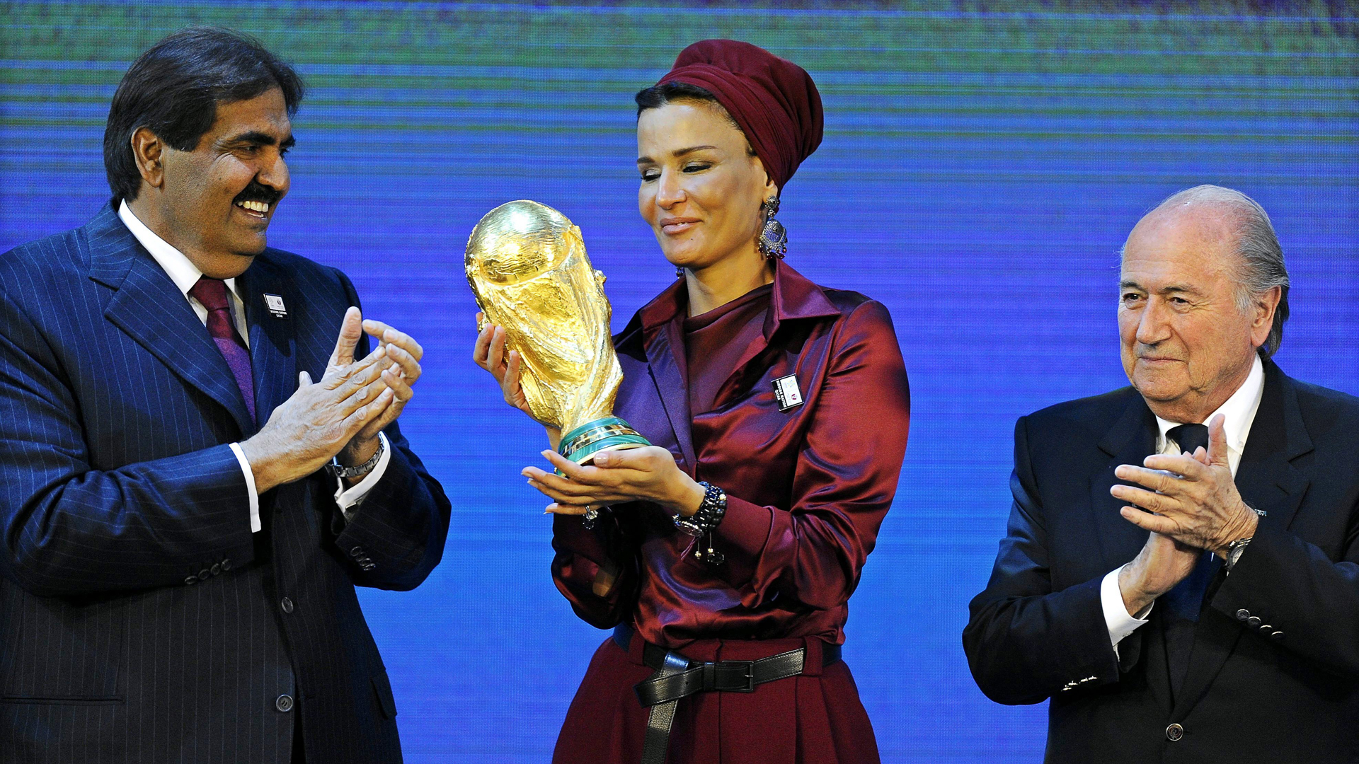 Scheicha Musa bei der Präsentation des WM-Pokals im Jahr 2010 mit ihrem Sohn , dem Emir von Katar, und dem damaligen FIFA-Chef Sepp Blatter. | picture alliance / dpa