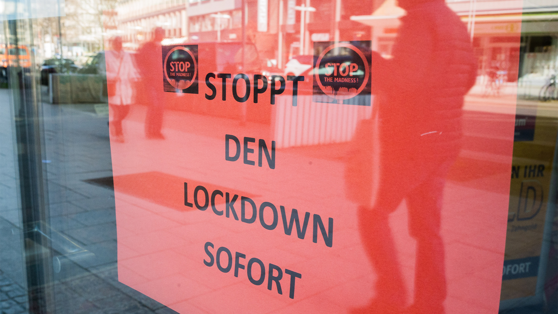 Ein Schild mit der Aufschrift "Stoppt den Lockdown sofort" hängt in der Eingangstür eines Ladengeschäftes.