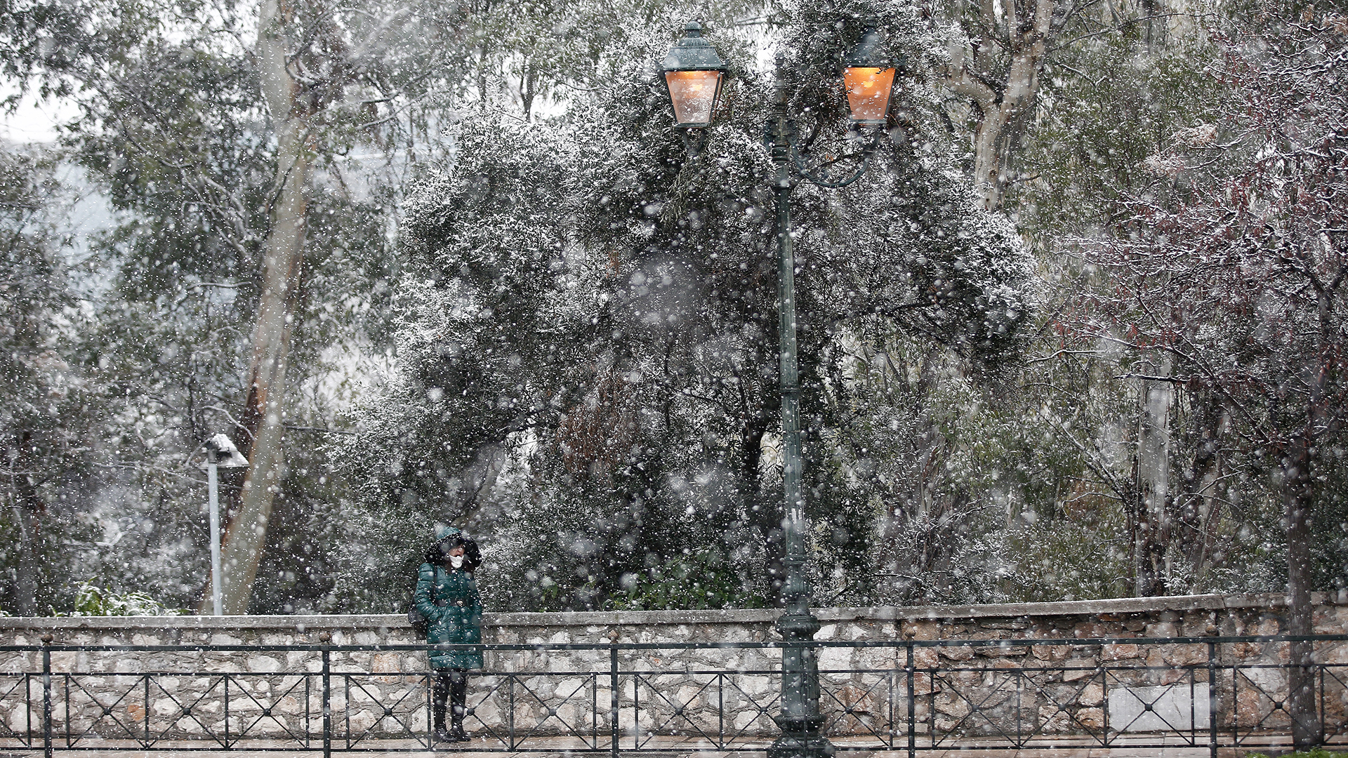 Eine Frau steht während eines Schneefalls im Zentrum von Athen an einer Straße. | EPA