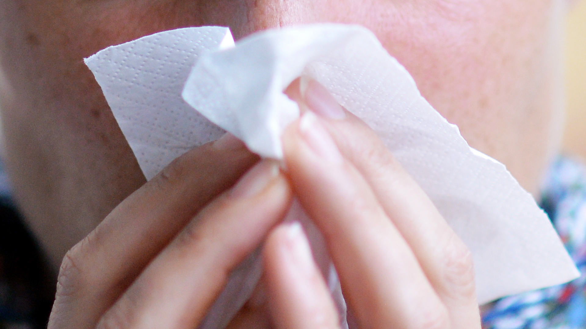 Eine Frau putzt sich die Nase mit einem Taschentuch. | dpa