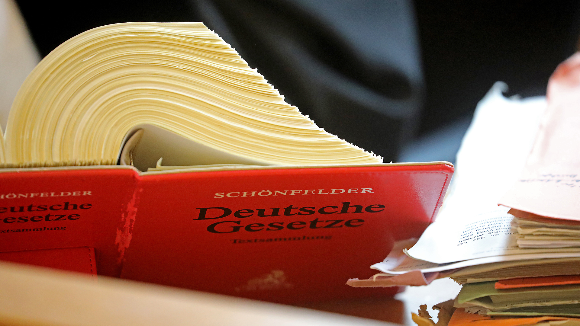 Ein Anwalt sitzt im Landgericht vor einem Textband "Deutsche Gesetze". | picture alliance/dpa