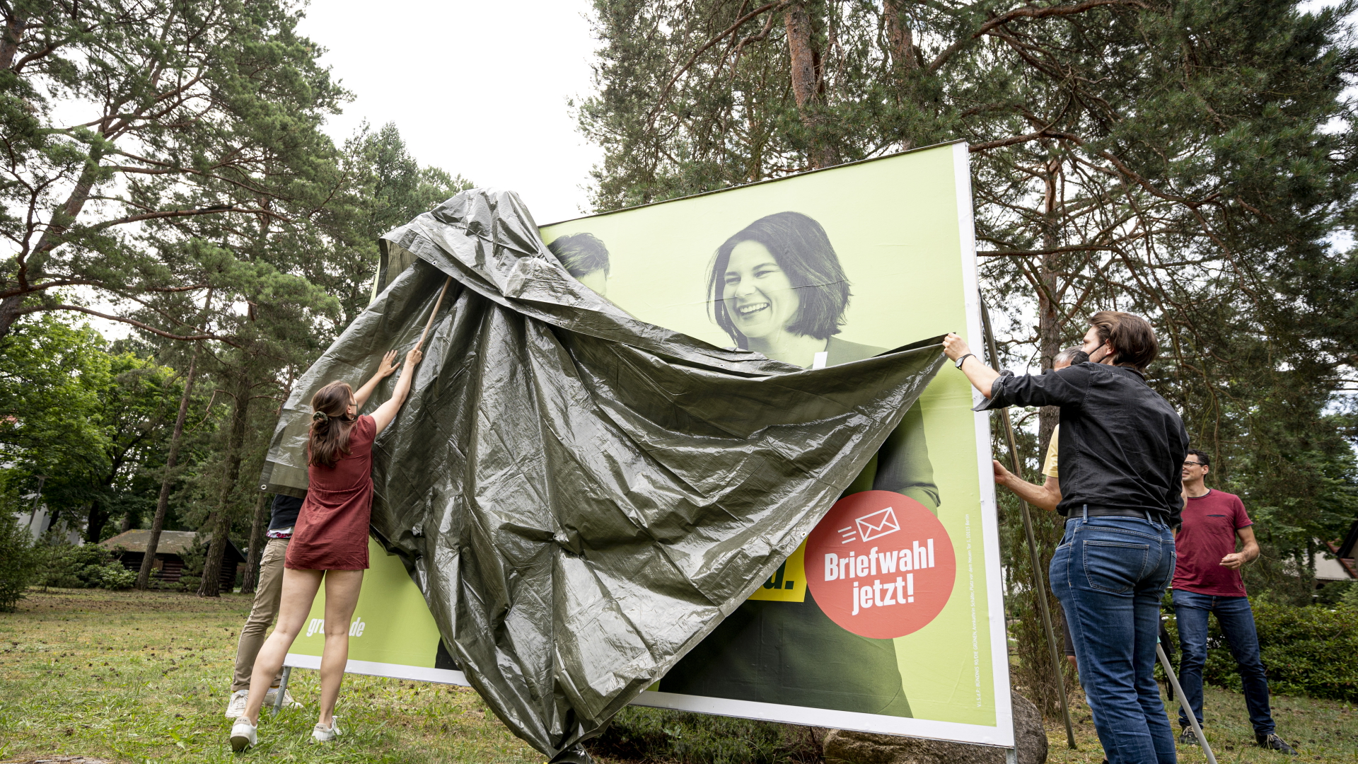 Mitglieder der Partei verdecken vor der Enthüllung das Großflächenplakat mit der Aufschrift "Unser Land kann viel, wenn man es lässt", das Teil der Grünen-Kampagne "Bereit, weil Ihr es seid." | dpa