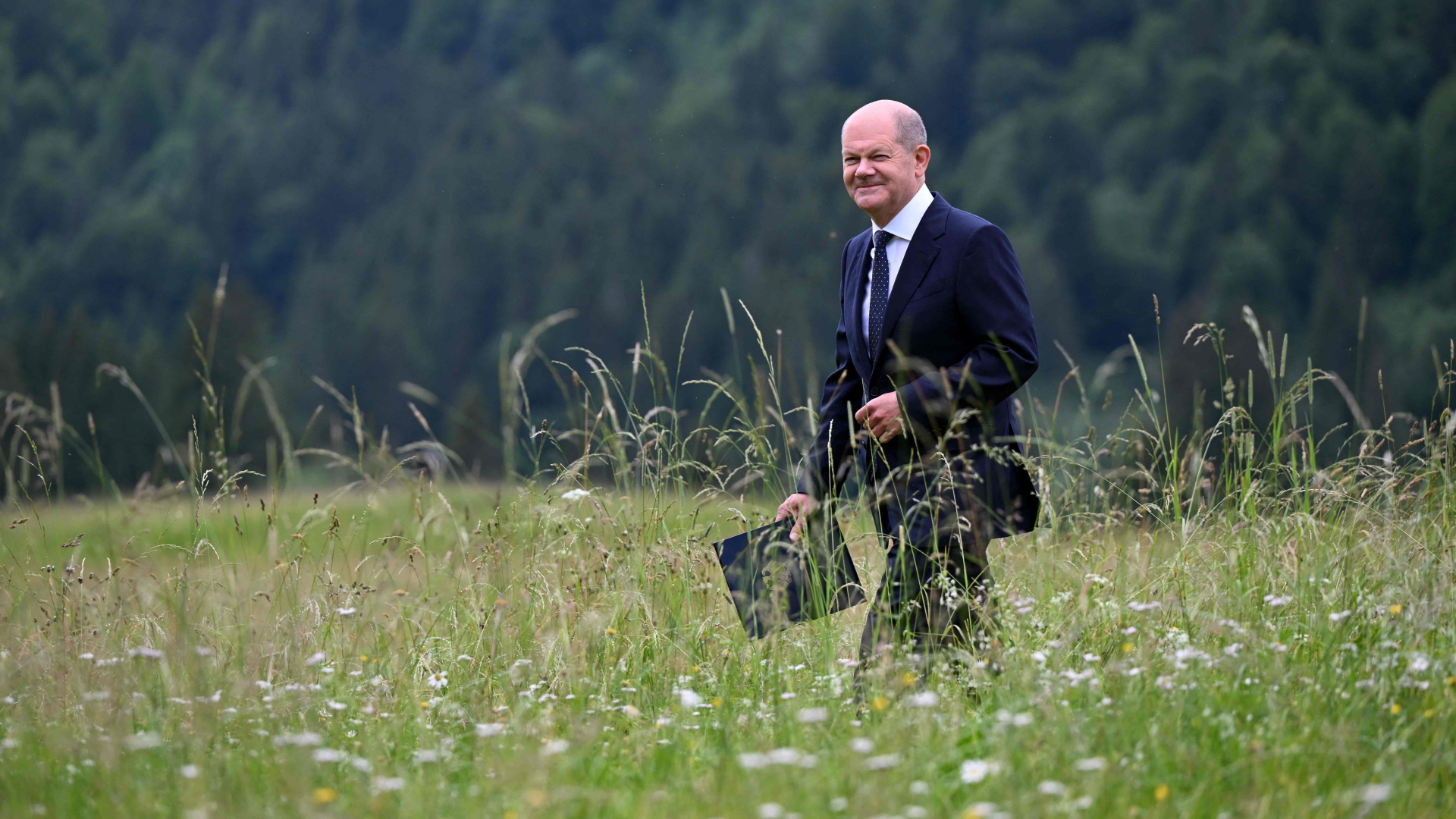 Bundeskanzler Olaf Scholz geht über eine Blumenwiese 