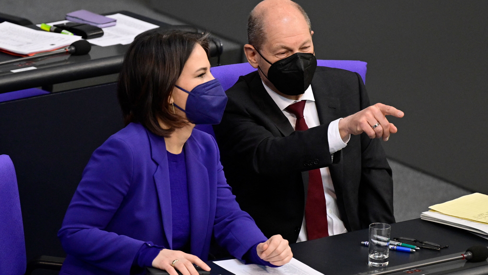 Bundeskanzler Olaf Scholz deutet auf etwas bei einer Sitzung des Bundestages, neben ihm sitzt Bundesaußenministerin Annalena Baerbock. Beide tragen Corona-Schutzmasken. | AFP