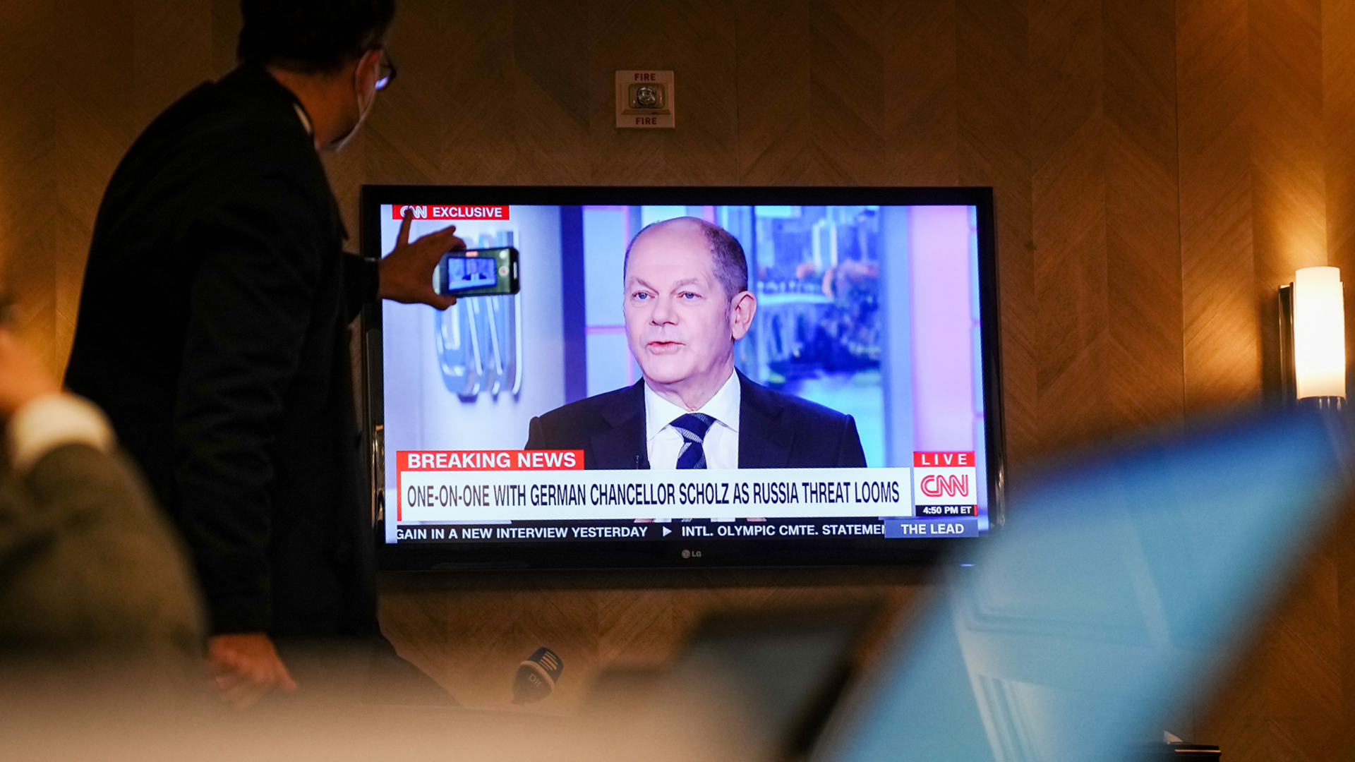 Ein Journalist macht ein Handyfoto vom Bildschirm, auf dem Scholz' CNN-Interview übertragen wird. | dpa