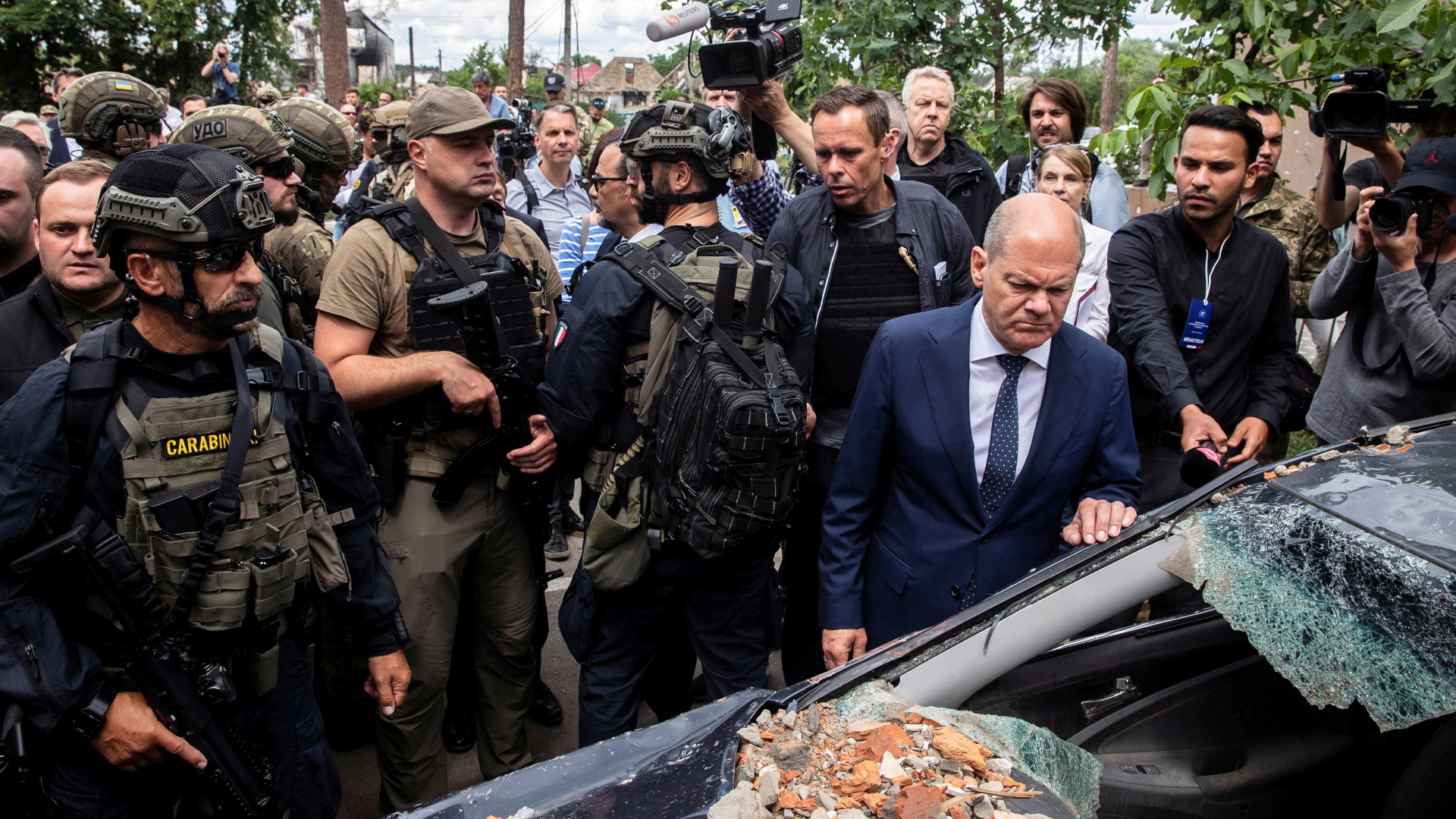 Olaf Scholz steht an einem zerschossenen Auto in Irpin, Kiew, umringt von Soldaten und Journalisten.  | REUTERS