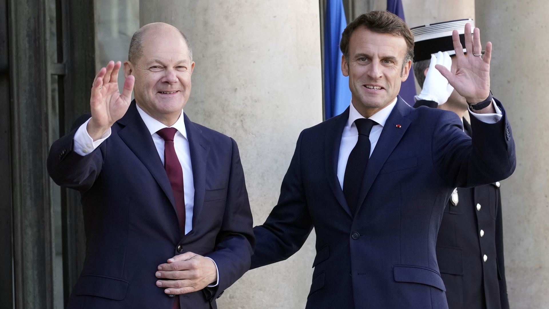 Olaf Scholz und Emmanuel Macron winken Arm in Arm der Presse zu (Archivbild) | dpa
