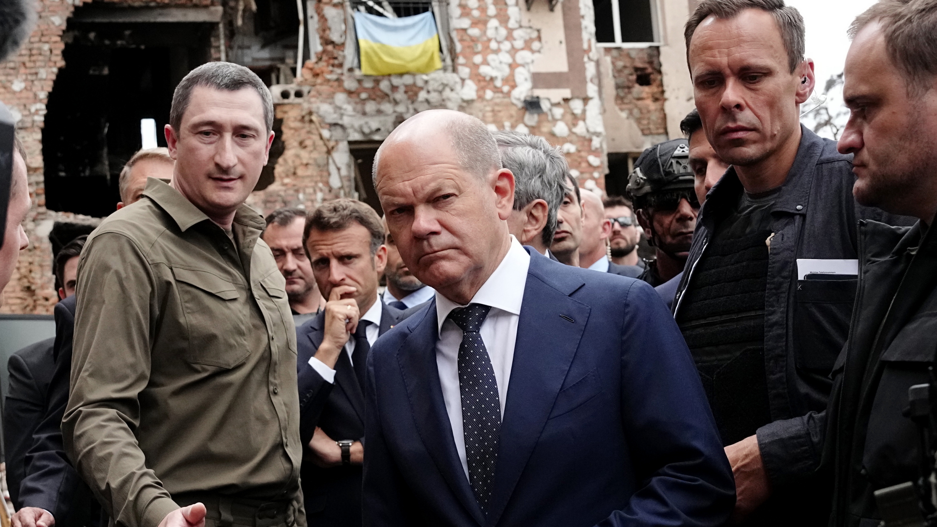 Scholz schaut bei einem Besuch in Irpin ernst in die Kamera, links neben ihm Oleksij Tschernyschow, der Sondergesandte des ukrainischen Präsidenten Selenskyj, und mittig der französische Präsident Macron,  | dpa