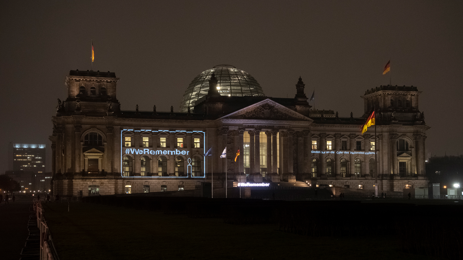 Der Schriftzug "#WeRemember" leuchtet am Reichstagsgebäude. | dpa