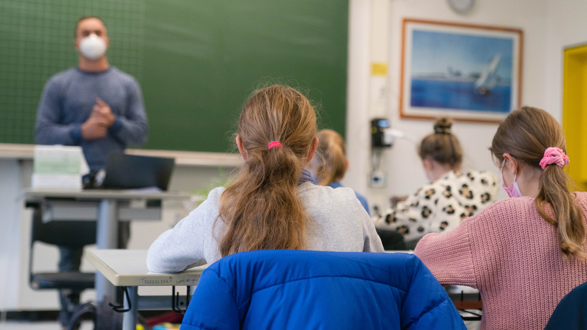 Schülerinnen und Schüler einer 5. Klasse eines Gymnasiums in Würzburg sitzen mit Mund-Nasen-Schutz im Klassenzimmer. | dpa