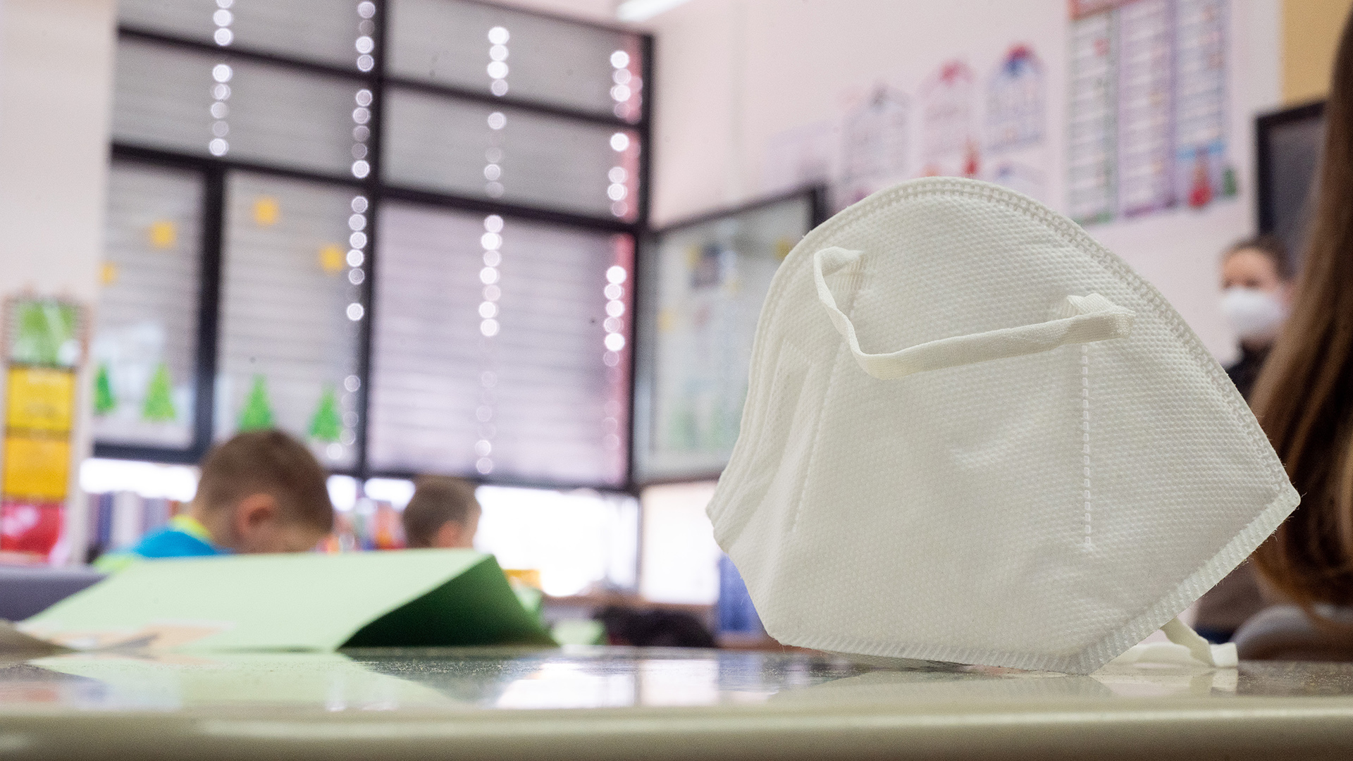 Eine FFP2-Maske liegt in einer ersten Klasse an einer Grundschule auf einem Tisch. | dpa