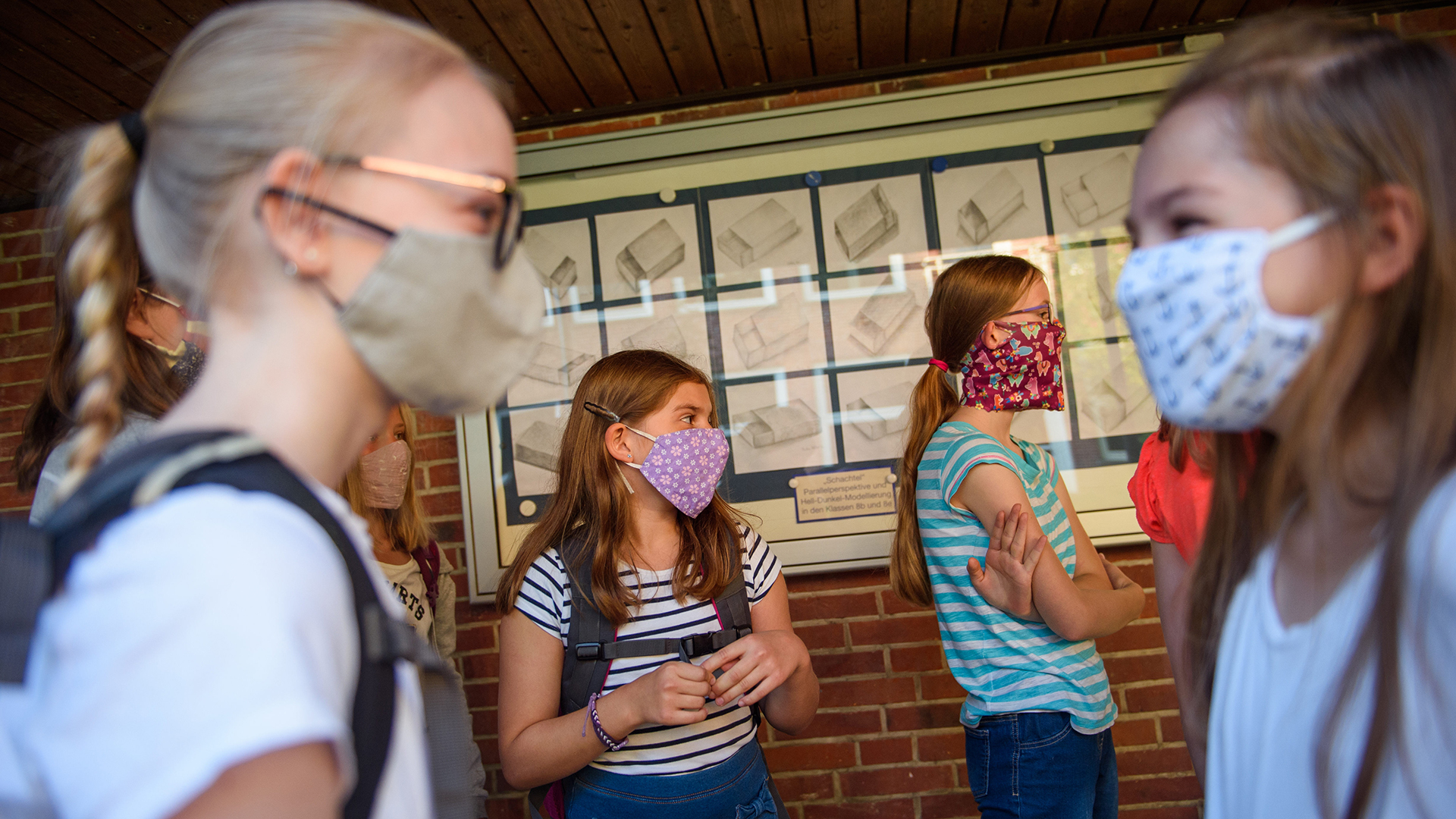 Schülerinnen mit Mundschutz stehen vor Beginn des Unterrichts zusammen. | dpa